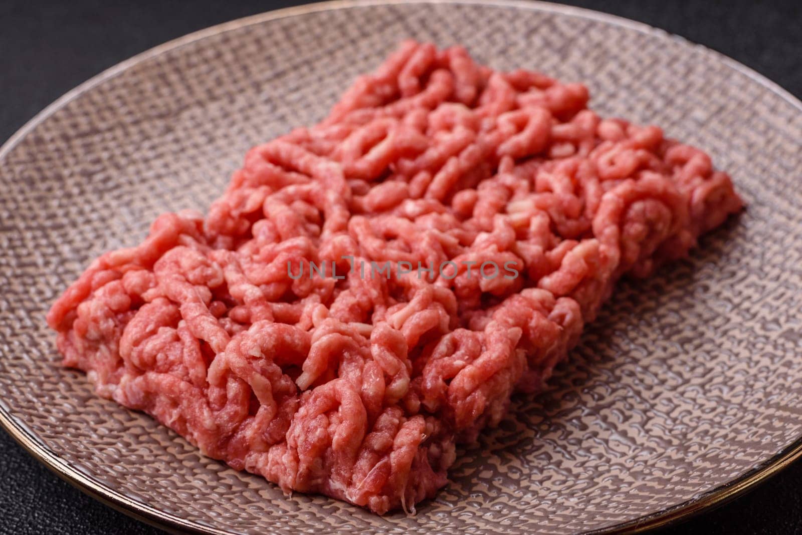 Stuffing or ground raw beef or pork with salt and spices on a black background
