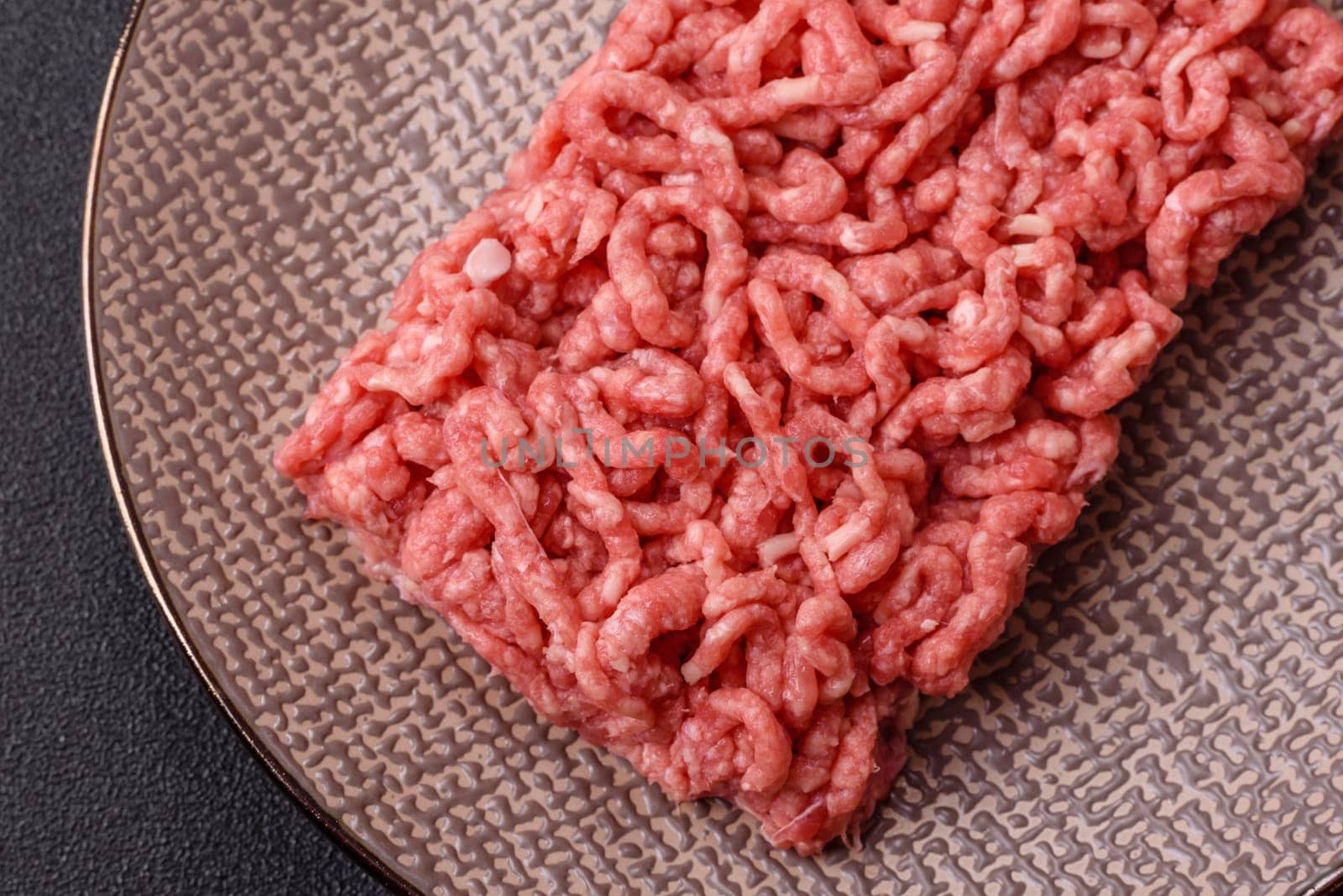 Stuffing or ground raw beef or pork with salt and spices on a black background
