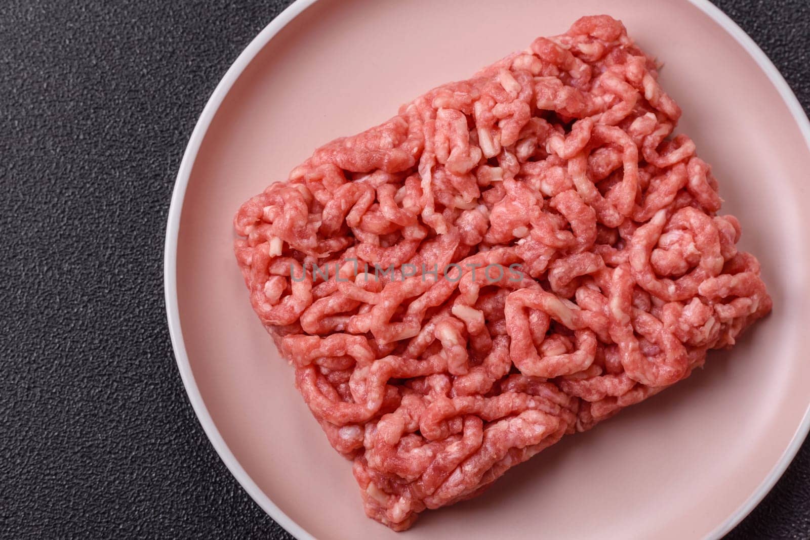 Stuffing or ground raw beef or pork with salt and spices on a black background