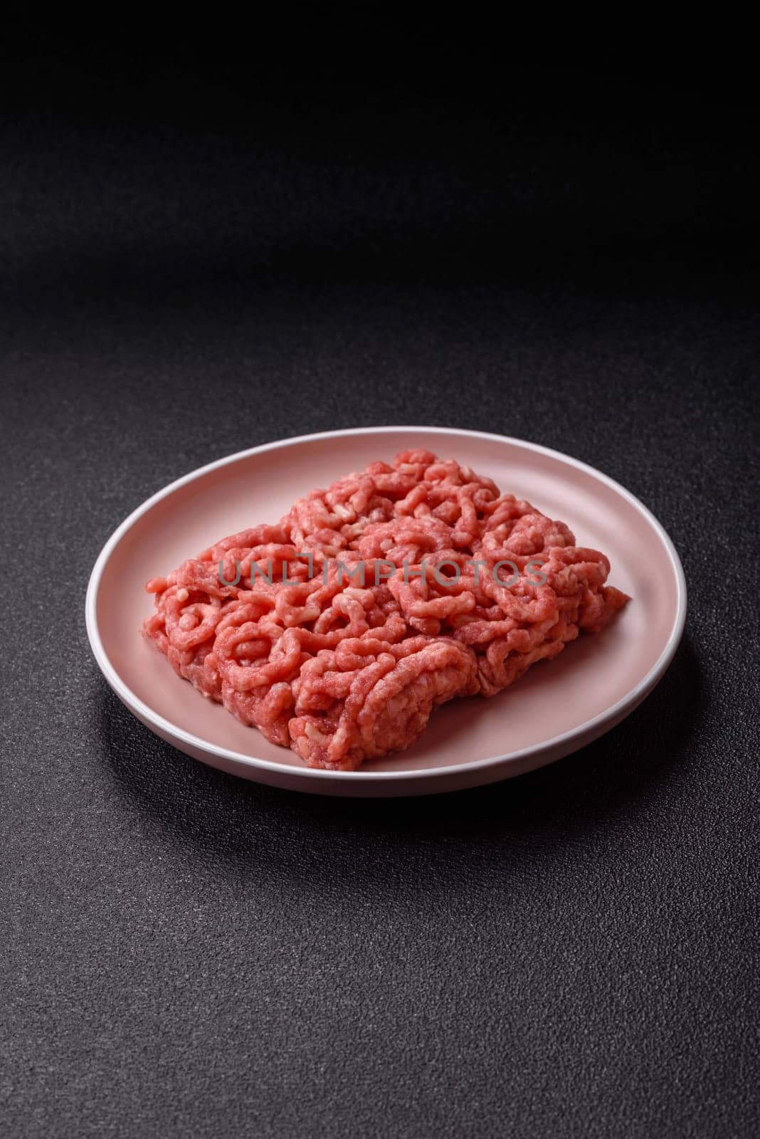 Stuffing or ground raw beef or pork with salt and spices on a black background