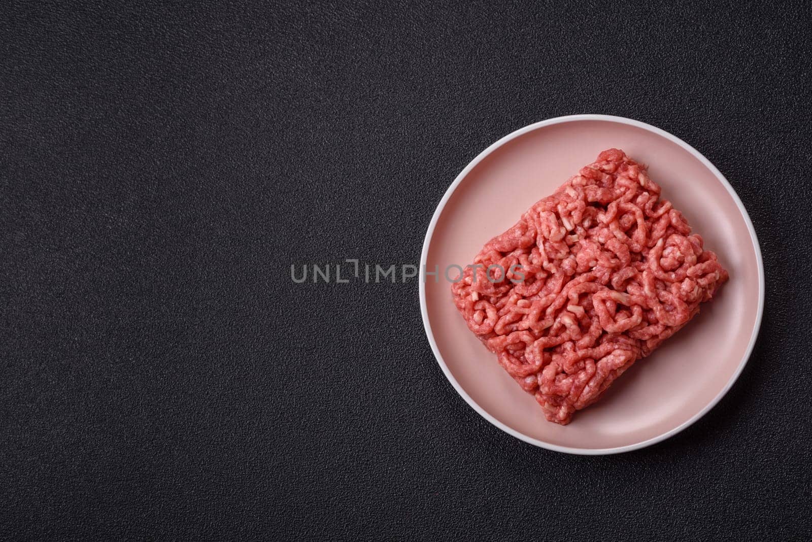 Stuffing or ground raw beef or pork with salt and spices on a black background