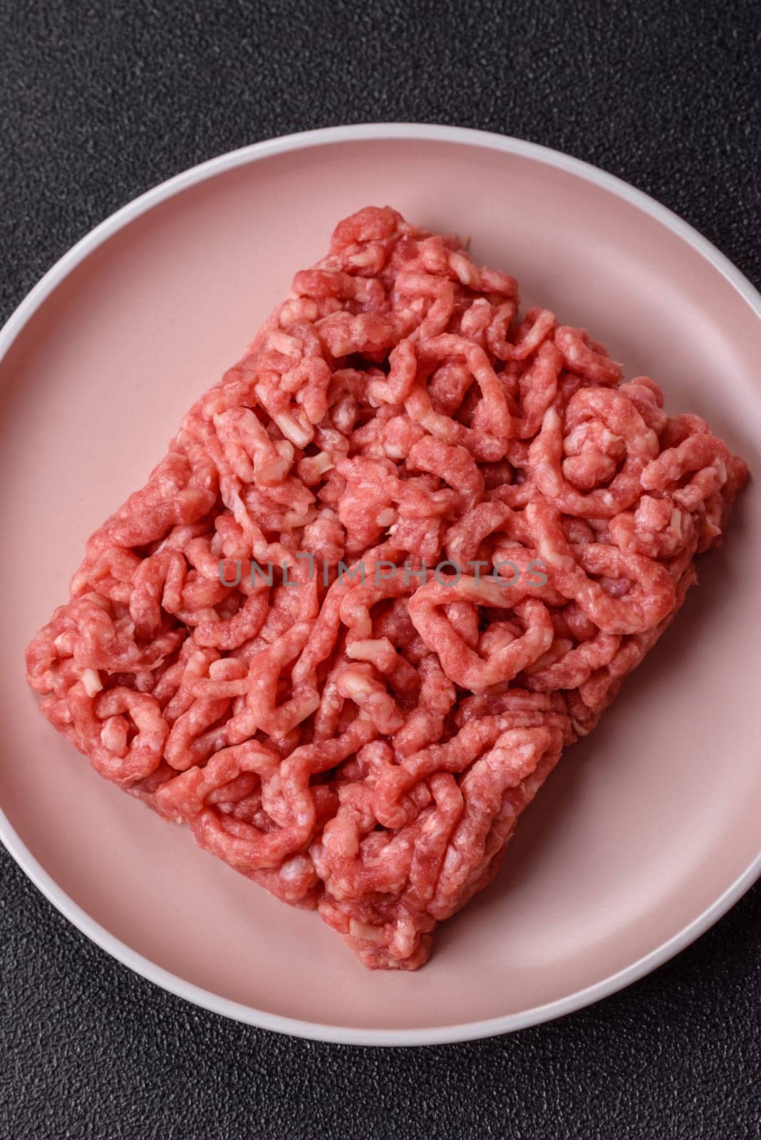 Stuffing or ground raw beef or pork with salt and spices on a black background