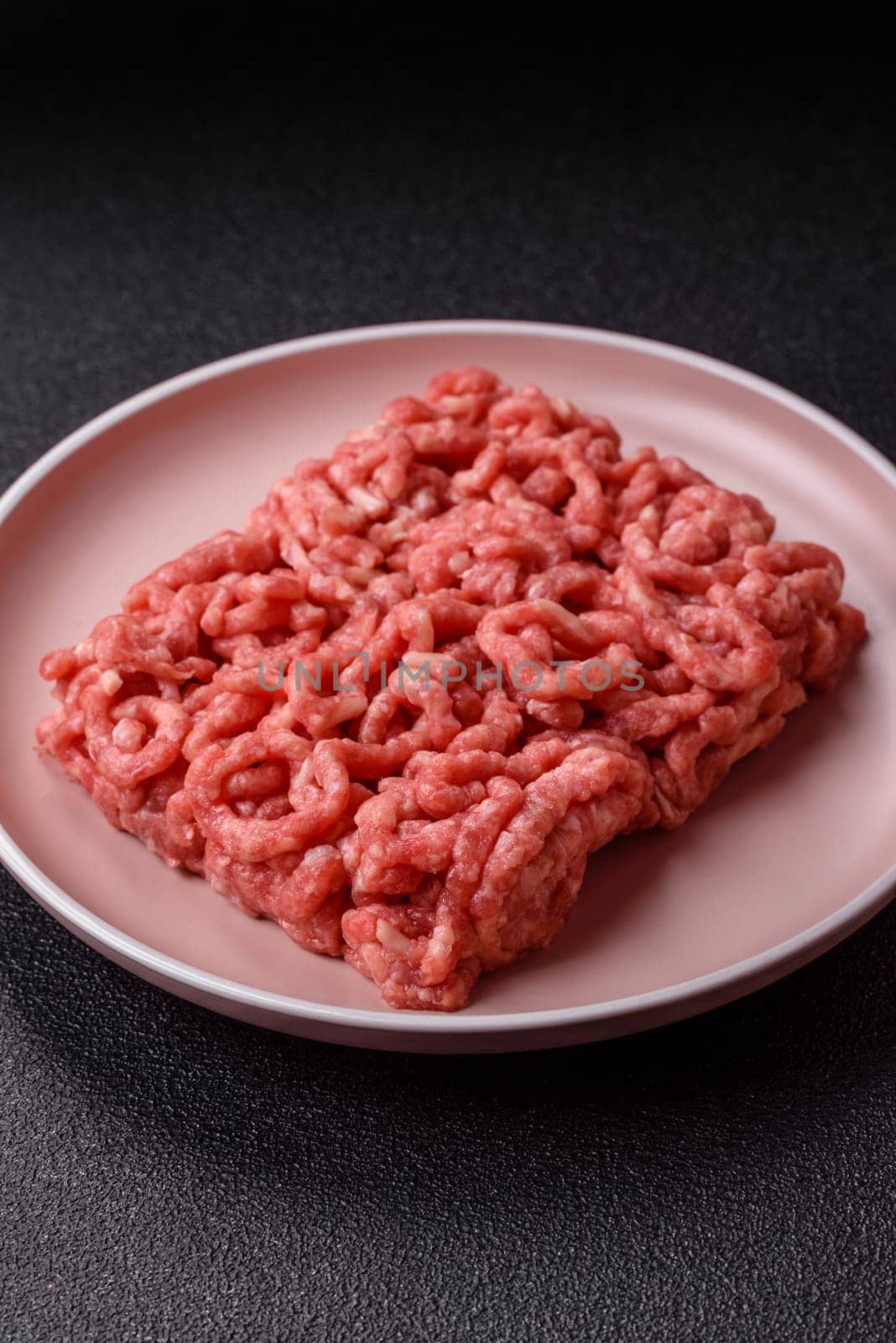 Stuffing or ground raw beef or pork with salt and spices on a black background