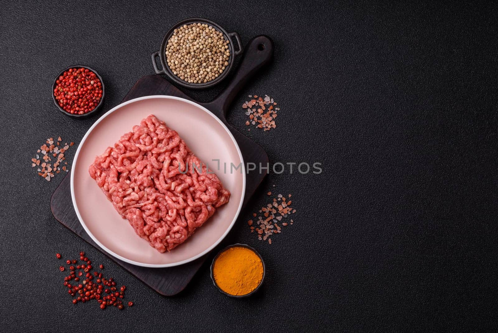 Stuffing or ground raw beef or pork with salt and spices on a black background