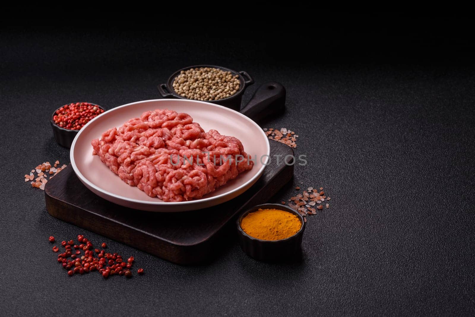 Stuffing or ground raw beef or pork with salt and spices on a black background