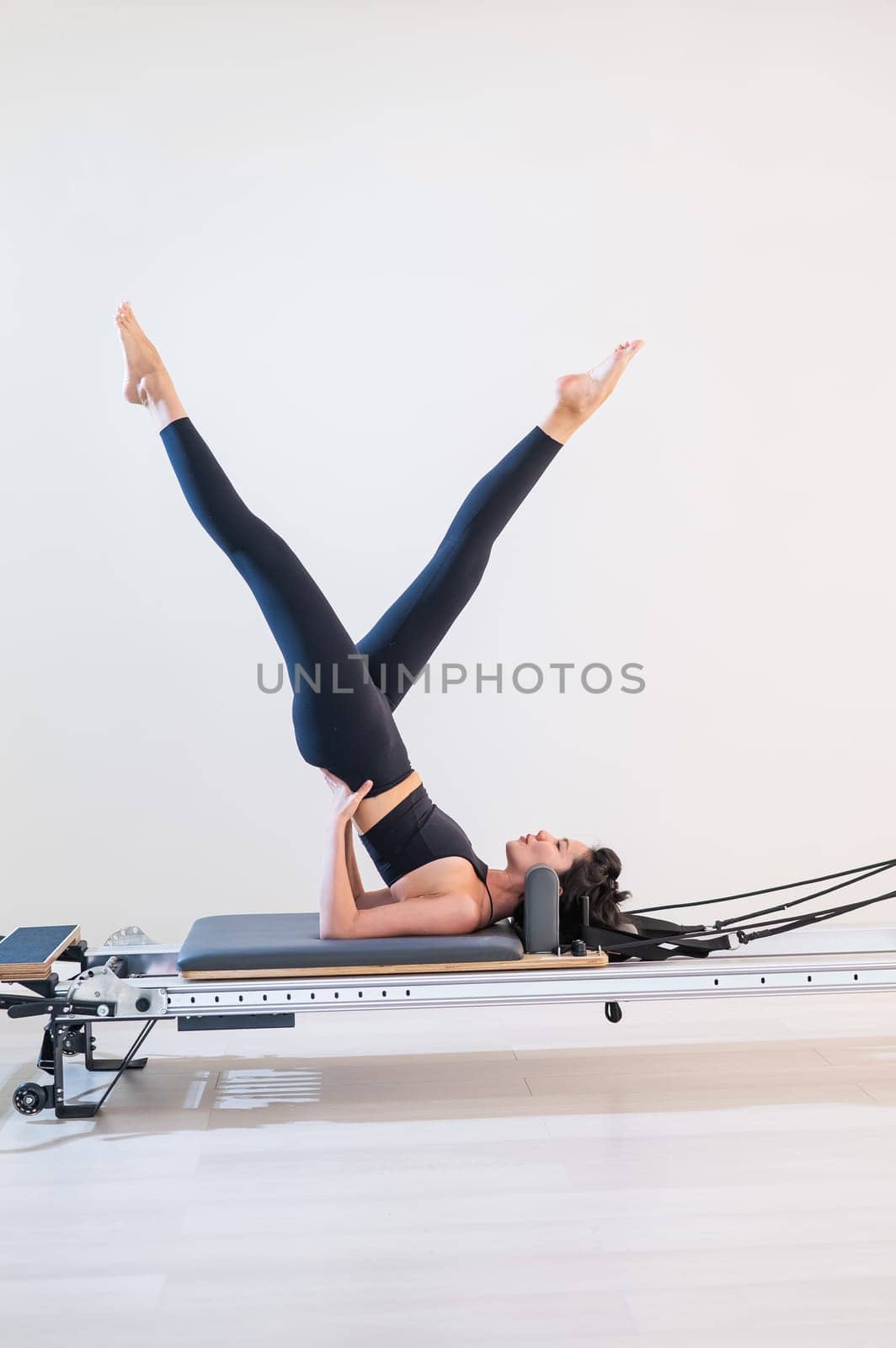 Asian woman doing pilates on reformer