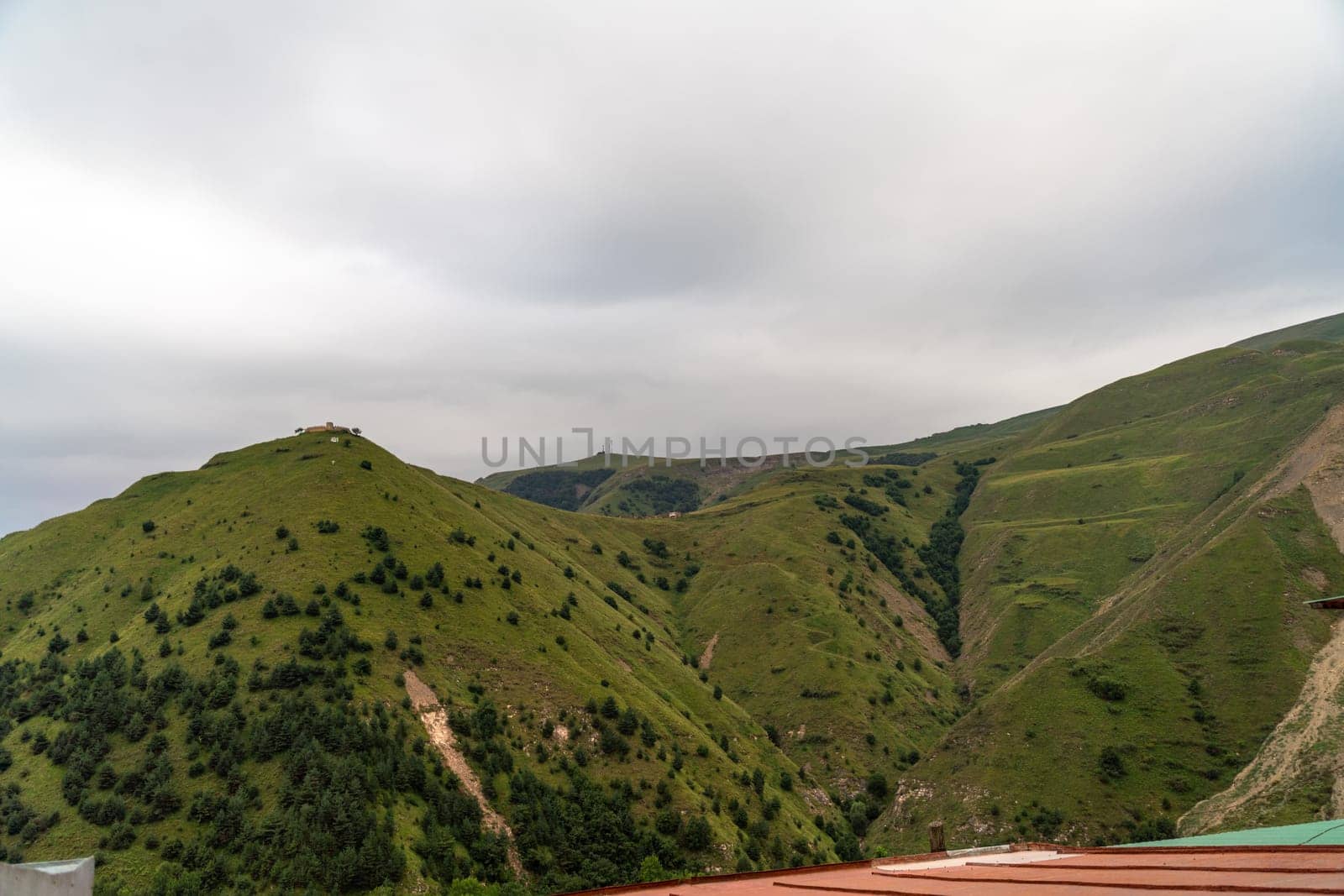 The mountains are covered in lush green trees and the sky is cloudy. The scene is peaceful and serene, with the mountains providing a beautiful backdrop