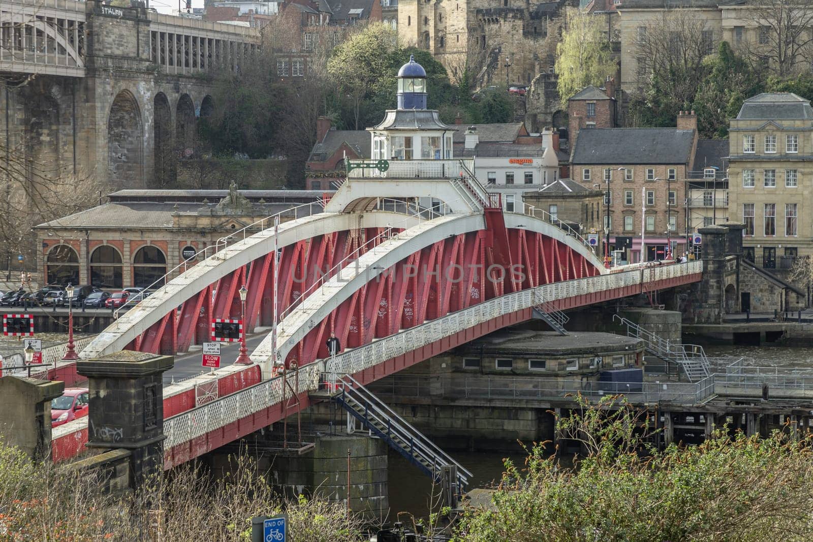 Newcastle, UK - Apr 11, 2025 - A view of The Iconic Swing bridge or Swing span bridge spanning spanning the River Tyne with historical buildings at the background in Newcastle Upon Tyne in the North East of England. The pedestrian bridge, use it as your Wallpaper, Poster and Space for text, Selective focus.