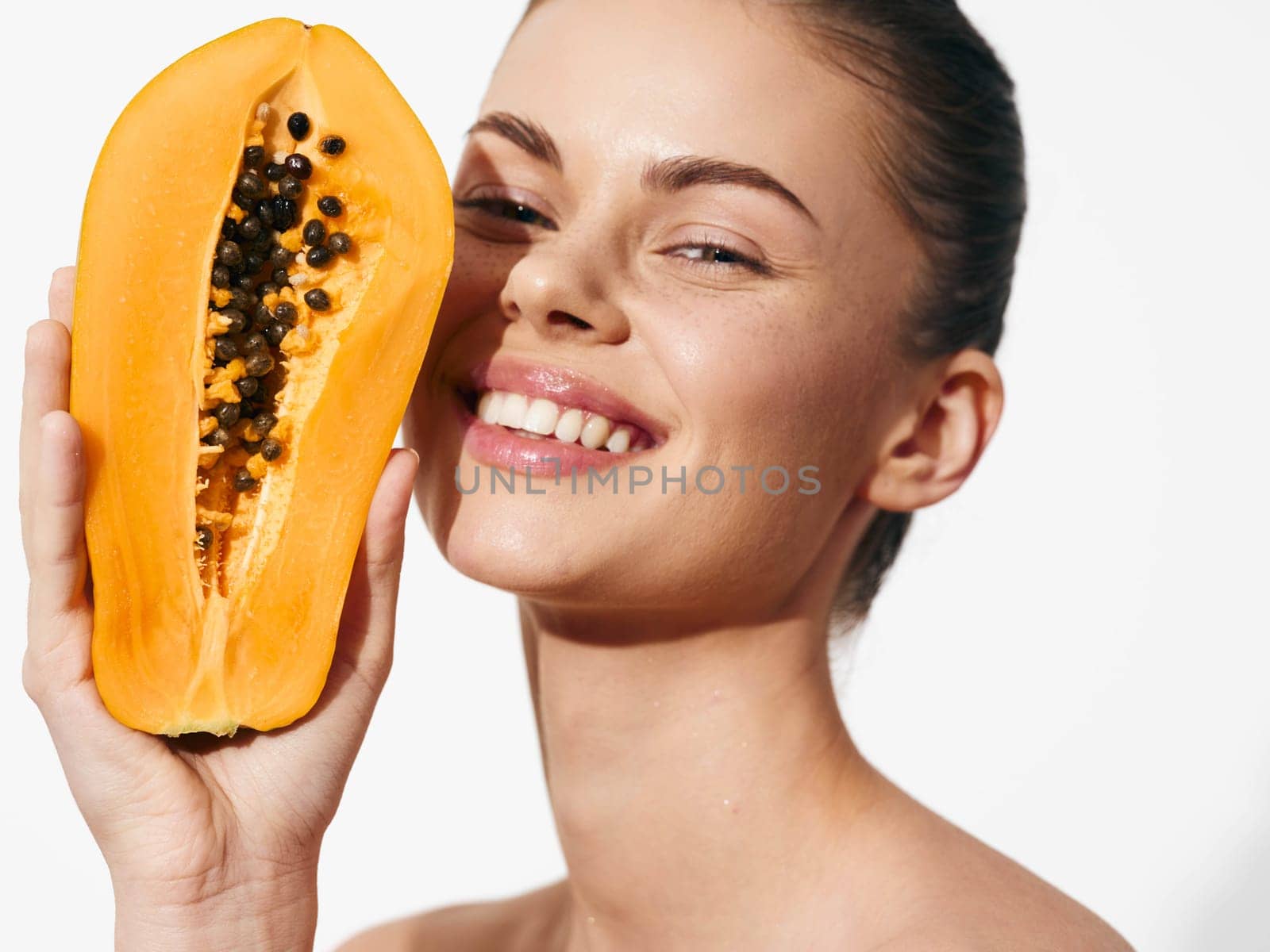 Smiling woman holding fresh papaya in front of face, tropical fruit concept for healthy eating and natural skincare advertising