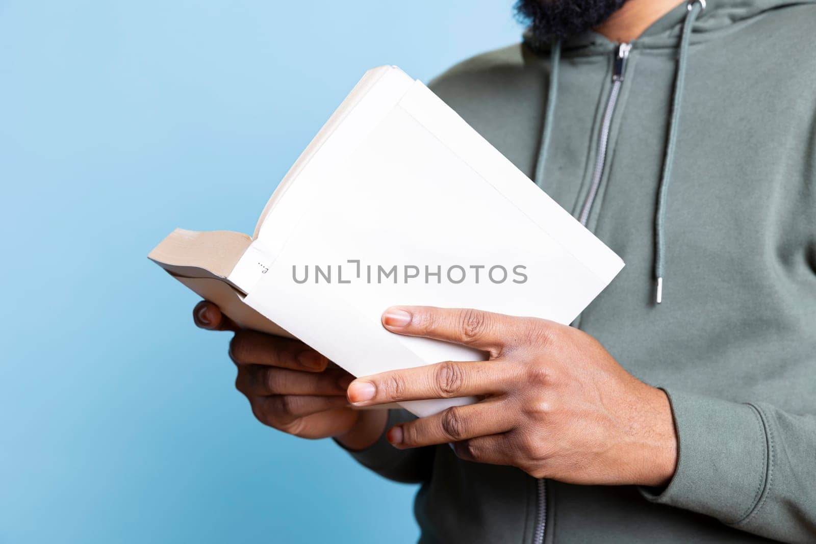 African american man reading book aloud and narrating story for audience. Person enjoying literature novel, reciting from pages, entertaining spectators against studio background. Close up.