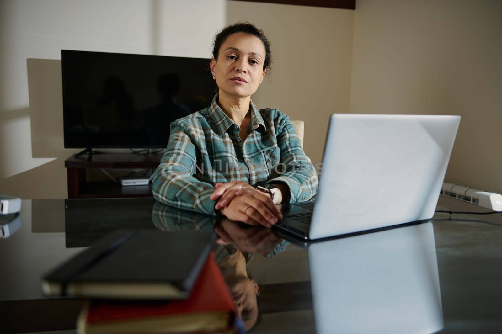 This image shows a confident woman sitting at a desk with a laptop, embodying professionalism, entrepreneurship, and focus in a modern home office environment.