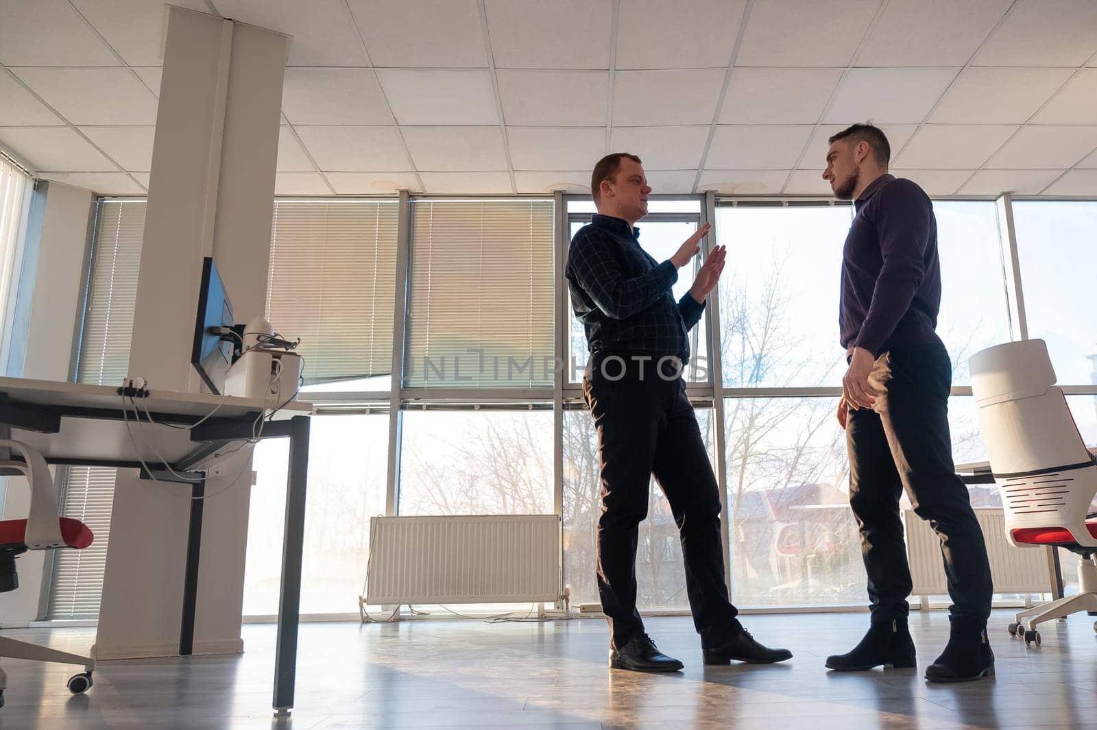 Two Caucasian men talking at work in the office