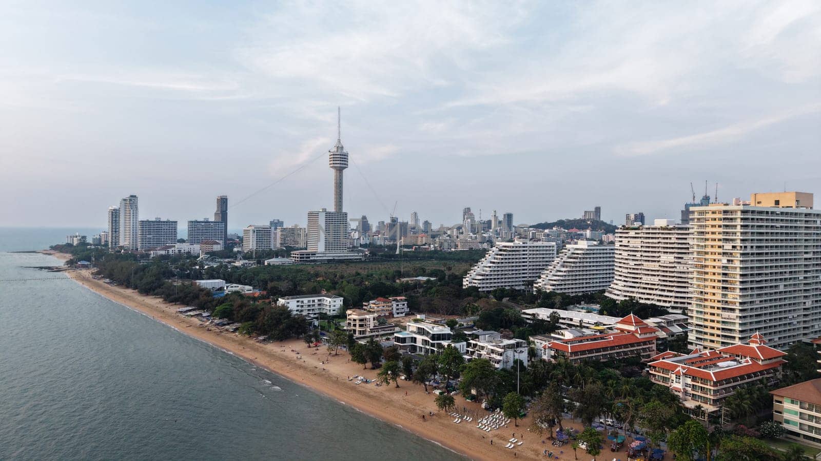 Aerial view of pattaya beach during sunset, showcasing the coastline with hotels, resorts, and the iconic pattaya park tower dominating the skyline