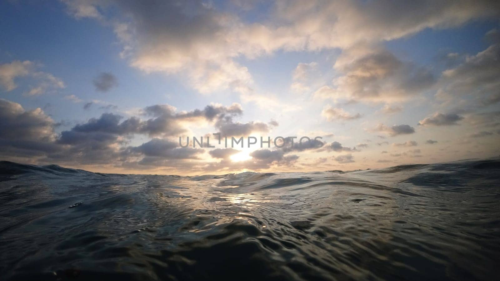 Golden sunset light reflecting on calm ocean waves beneath a cloudy sky, creating a serene and peaceful atmosphere that evokes tranquility and beauty in nature