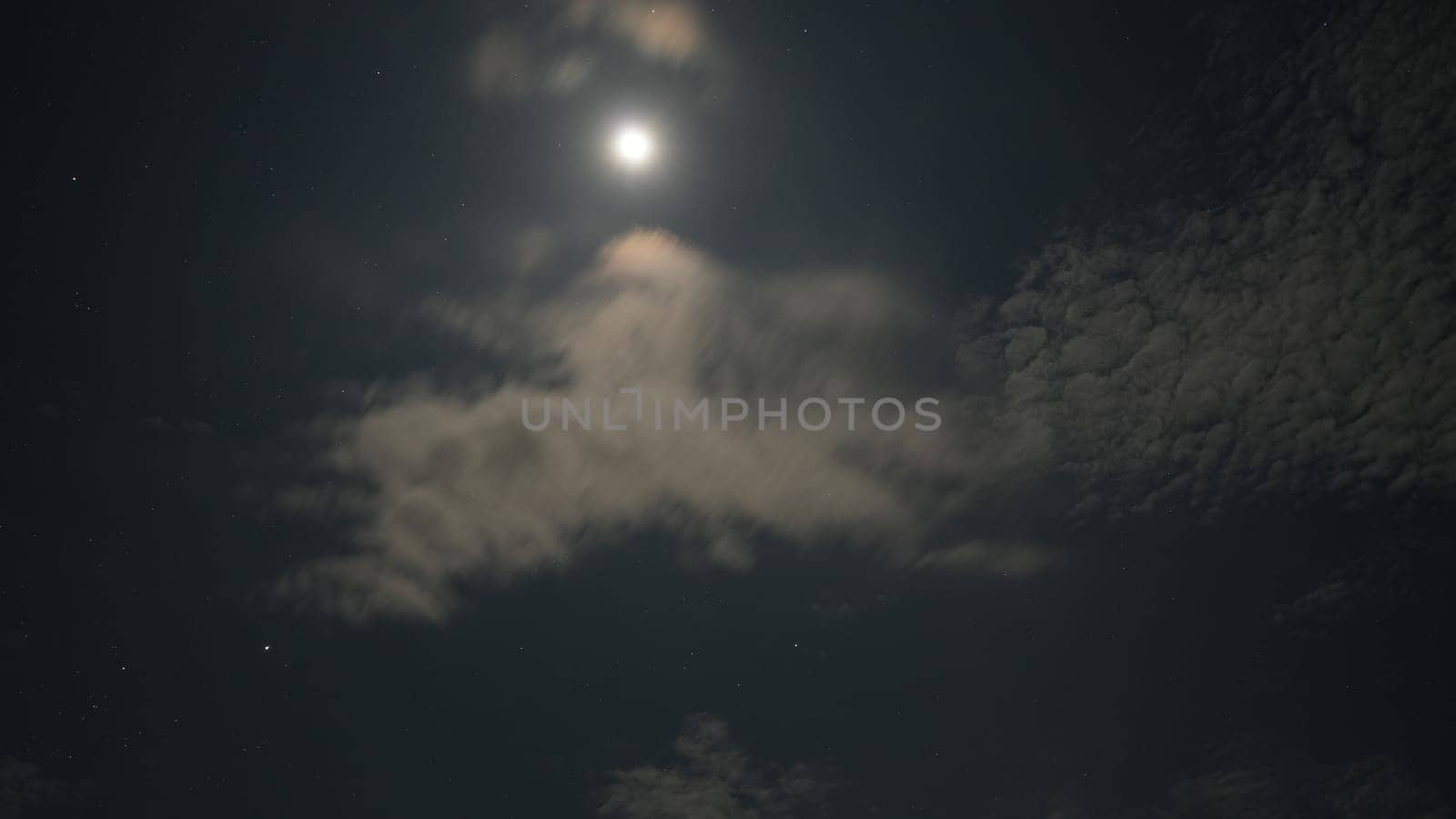 Bright moon illuminating the dark night sky, casting its glow through wispy clouds and creating a stunning celestial scene filled with beauty and tranquility