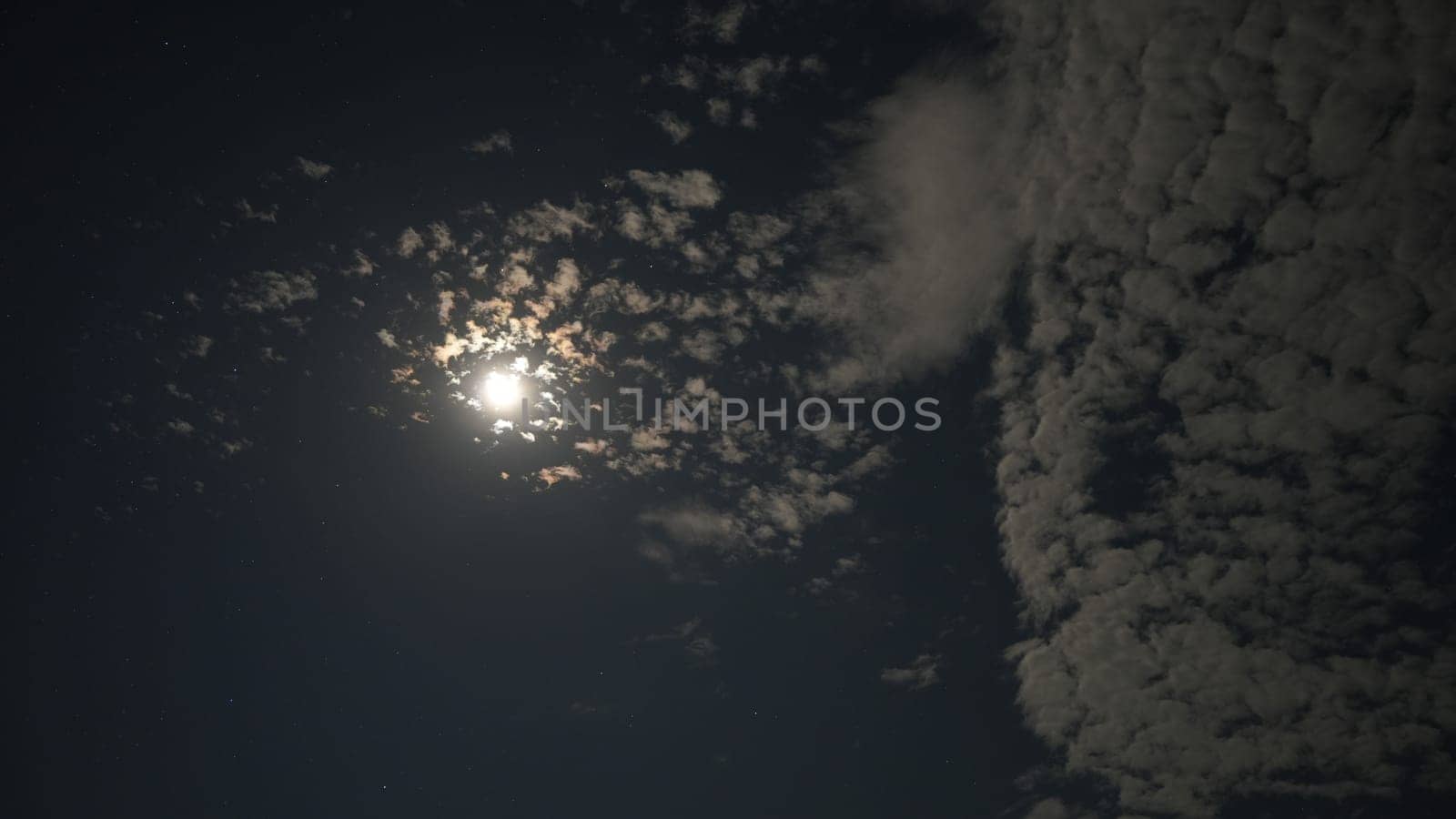 Bright moon illuminating the night sky, casting a soft glow through scattered clouds, creates a dramatic and ethereal atmosphere, inviting a sense of tranquility and wonder