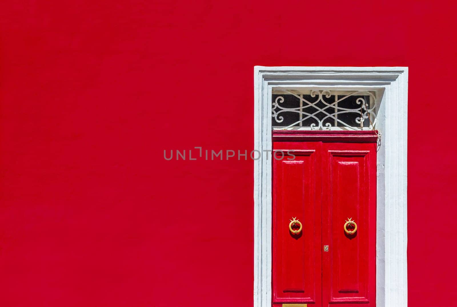 Minimalist architectural photography. Red wall of residential building facade with red door in white wooden frame.