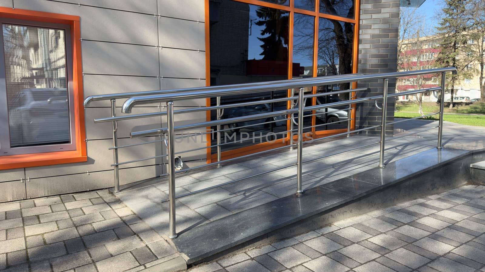 Ramp for entering building for people with disabilities and parents with baby carriage. Convenient entrance with lifting ramp for comfortable ascent. Accessible environment in modern city