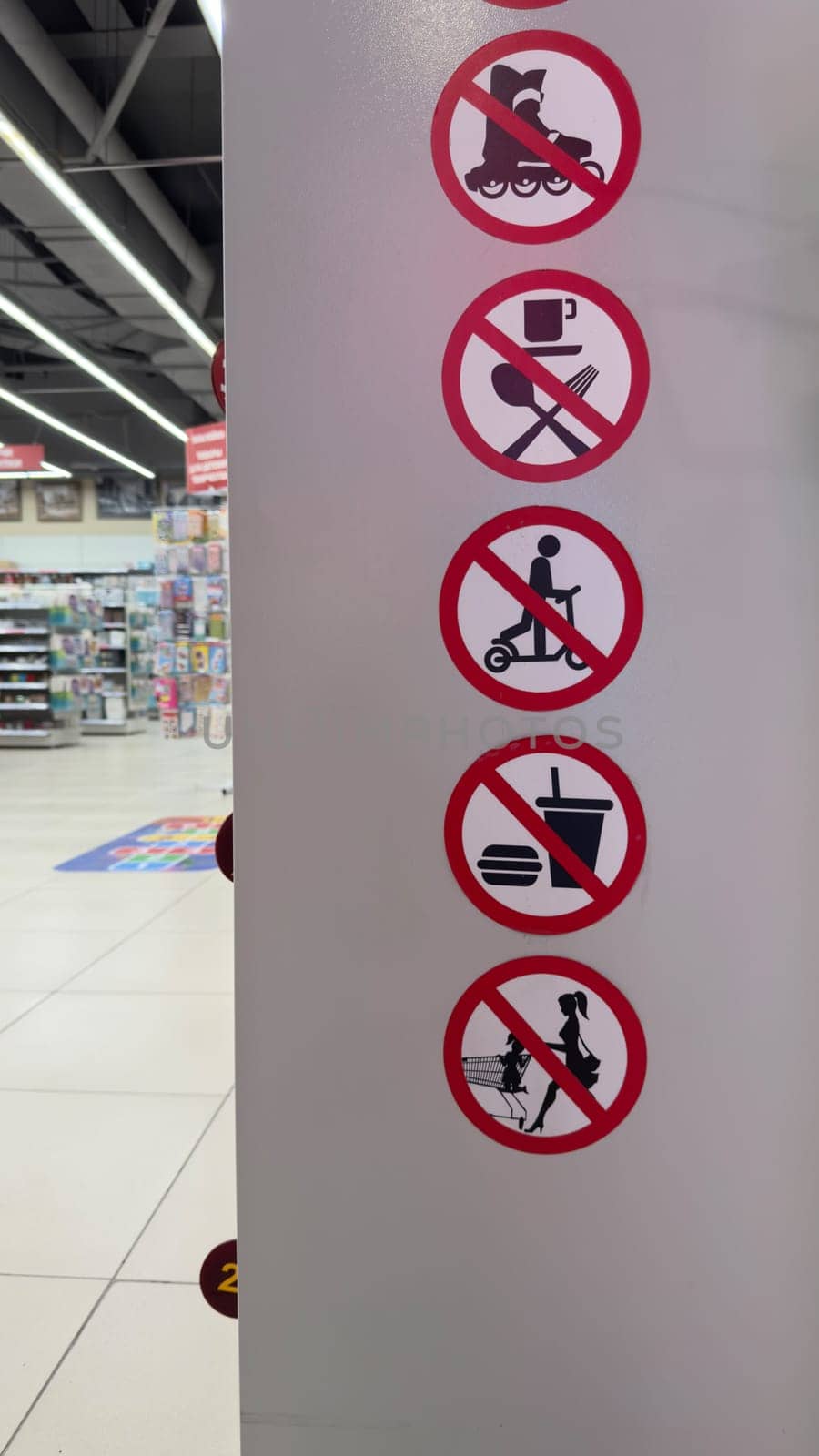 Vertical photo with sticker icons at entrance to store. Signs in red circle with prohibiting actions in store. Strict restrictions in retail space