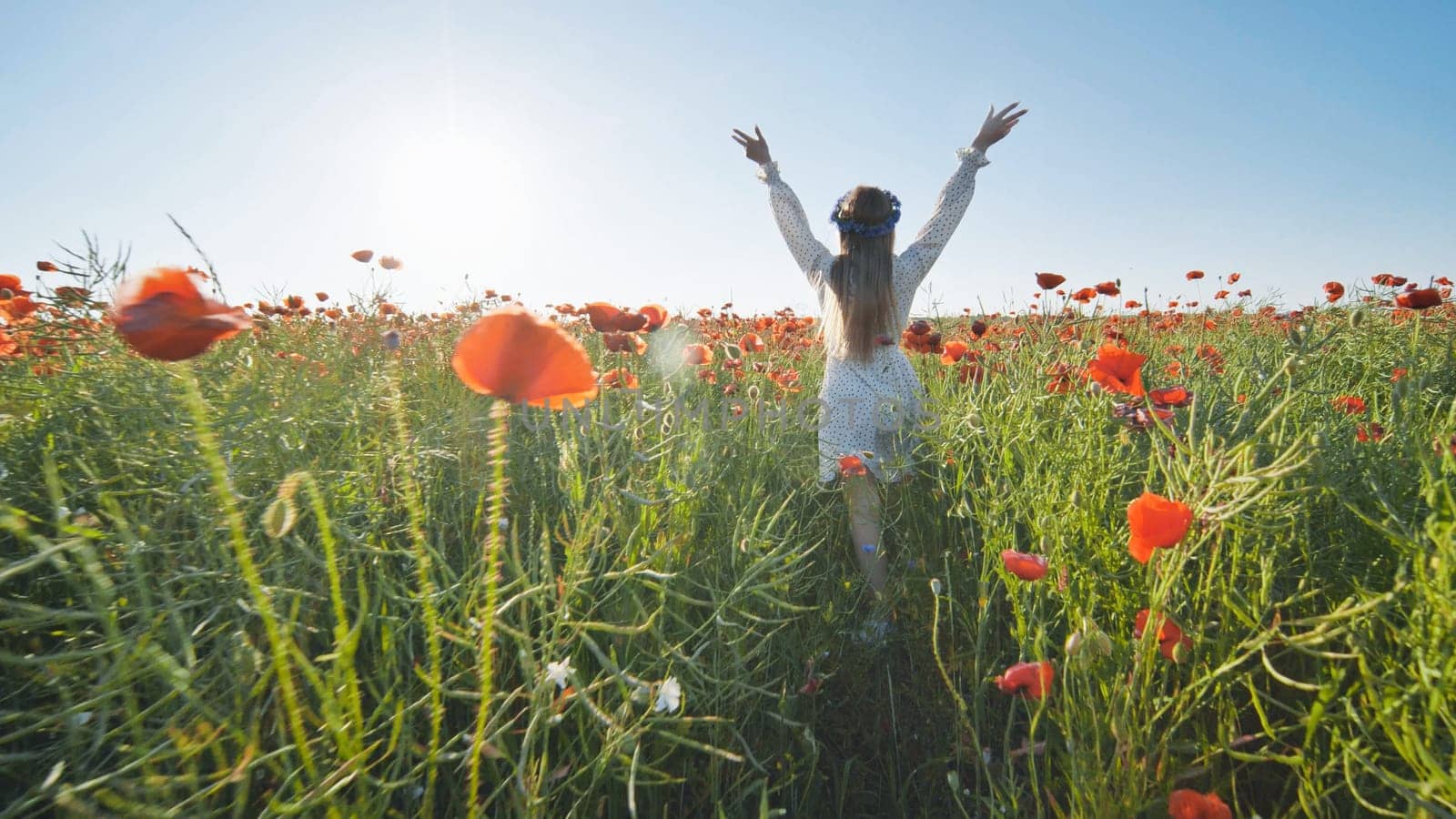 Carefree woman walking through a vibrant field of poppies, soaking up the warm summer sun and embracing the beauty of nature