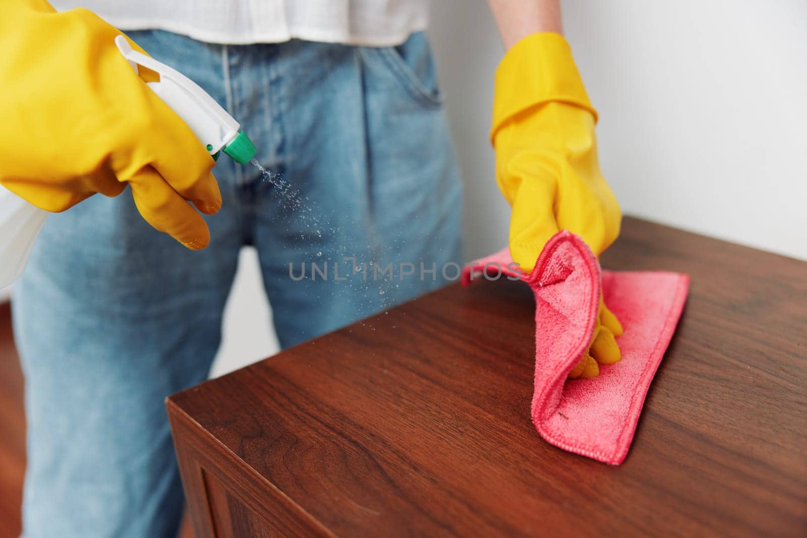 Woman in yellow gloves cleaning wooden table with rag and cleaning solution. cleaning concept, household chores, hygiene maintenance.
