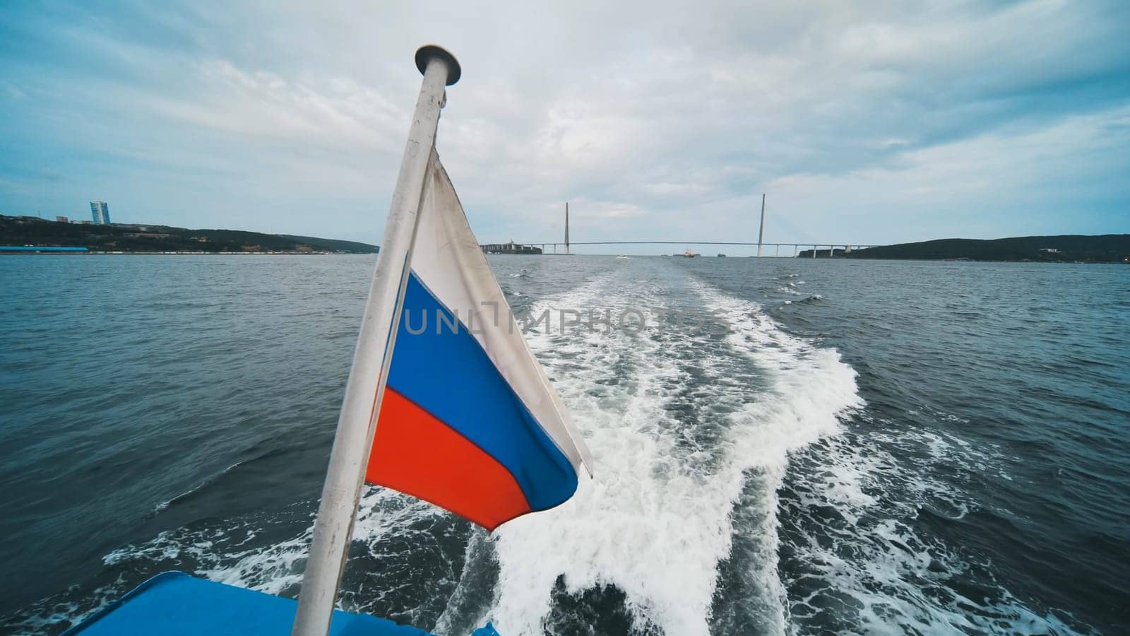 Russian flag waving from the stern of a boat sailing near the russky bridge in vladivostok, russia