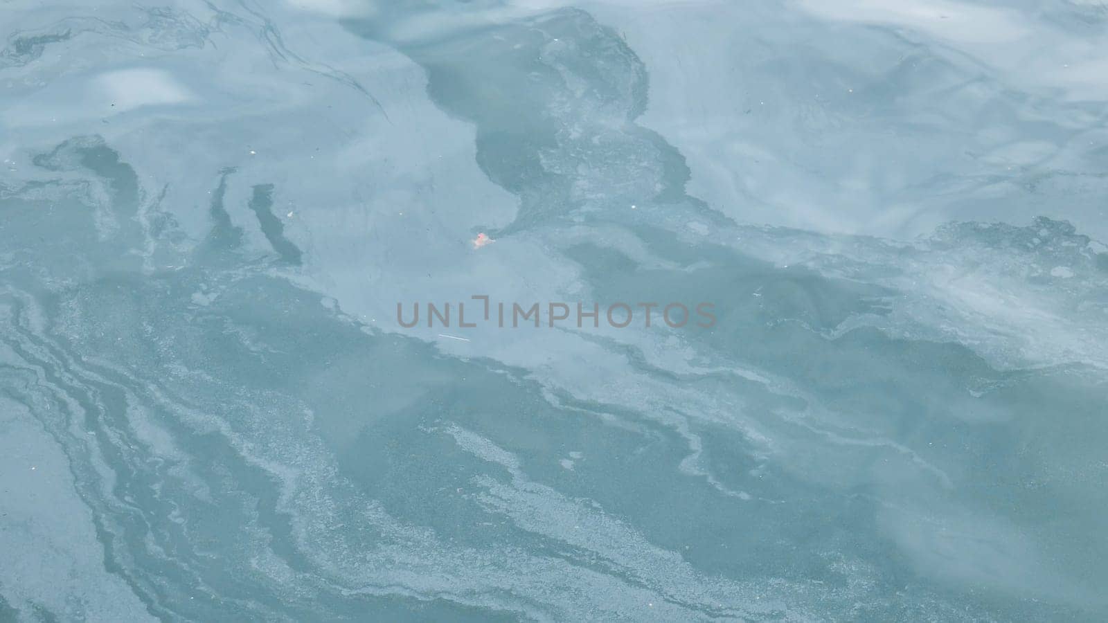Oil spill forming abstract patterns on the surface of the ocean, highlighting the devastating effects of pollution on marine ecosystems