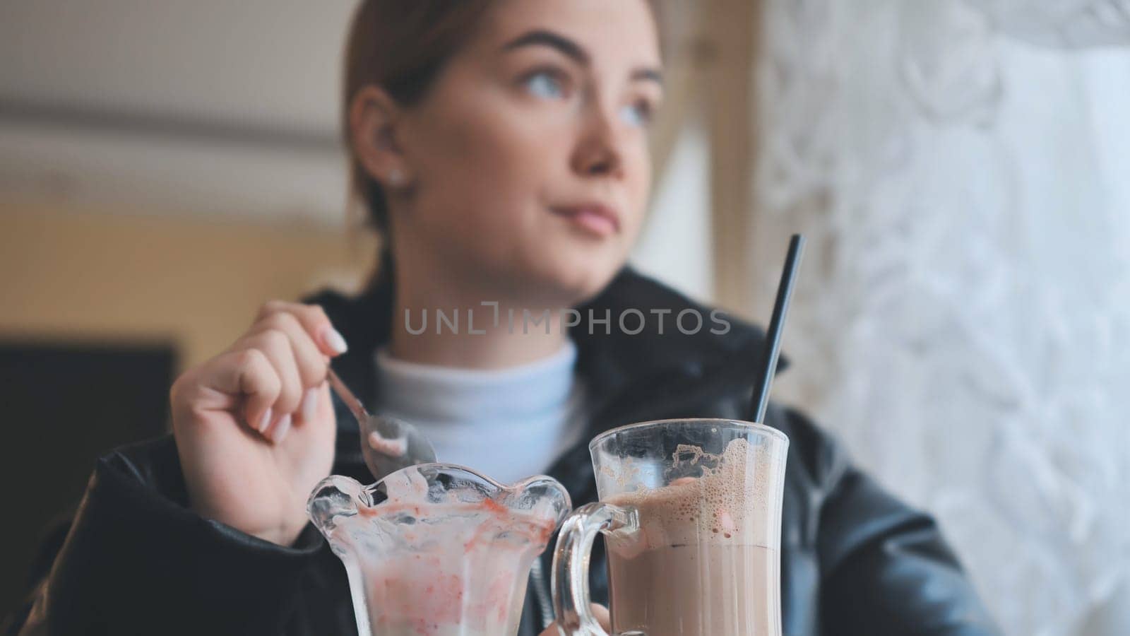 Customer is eating strawberry ice cream and drinking iced coffee in a cafe, enjoying a sweet treat