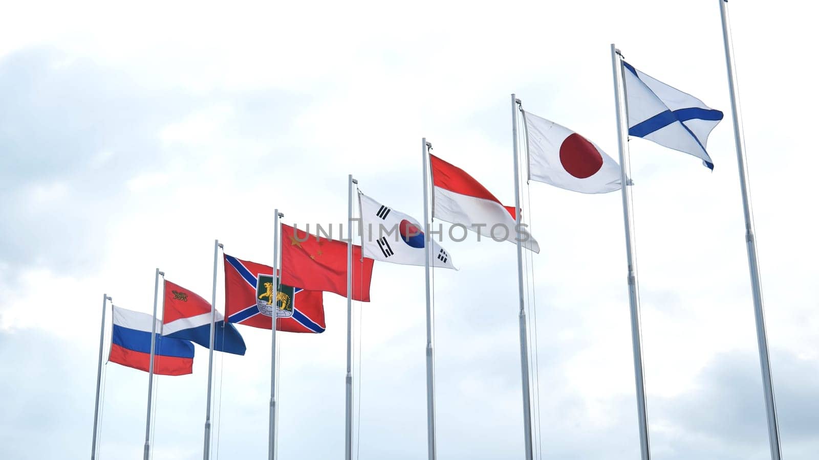 National flags fluttering together, symbolizing global unity and international collaboration within cloudy atmospheric backdrop