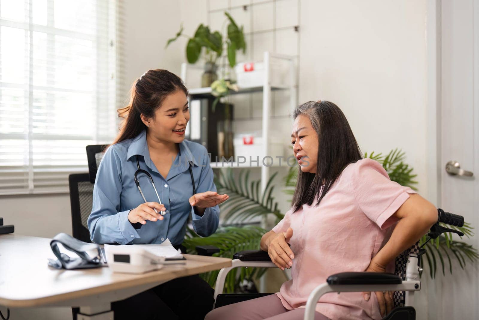 A caring nurse assists an elderly woman in a medical consultation, offering health advice in a pleasant and professional environment focused on patient well-being.