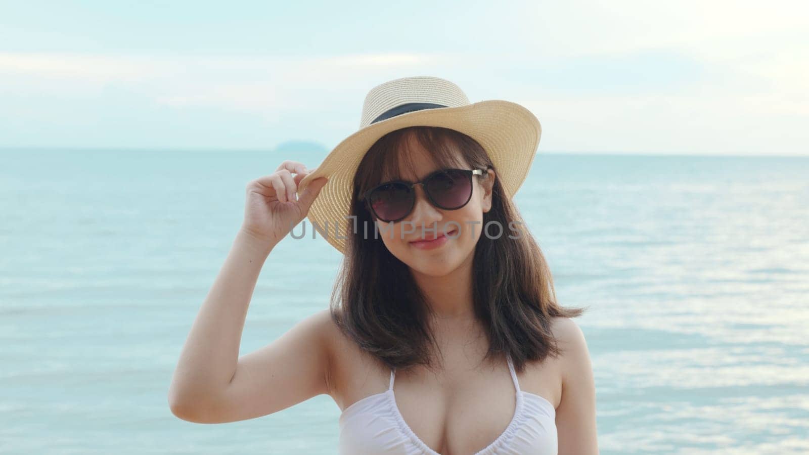 Beautiful Asian woman wear sungrass and hat turning back to looking camera and smiling at beach, Portrait of happy female in bikini having fun laughing on tropical in summer holiday