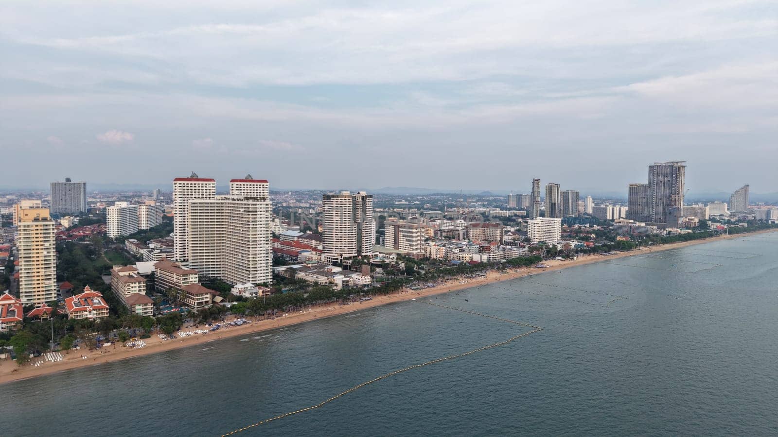 Modern buildings rising along the pattaya coastline create a stunning cityscape against the ocean backdrop as twilight approaches, blending urban development with natural beauty