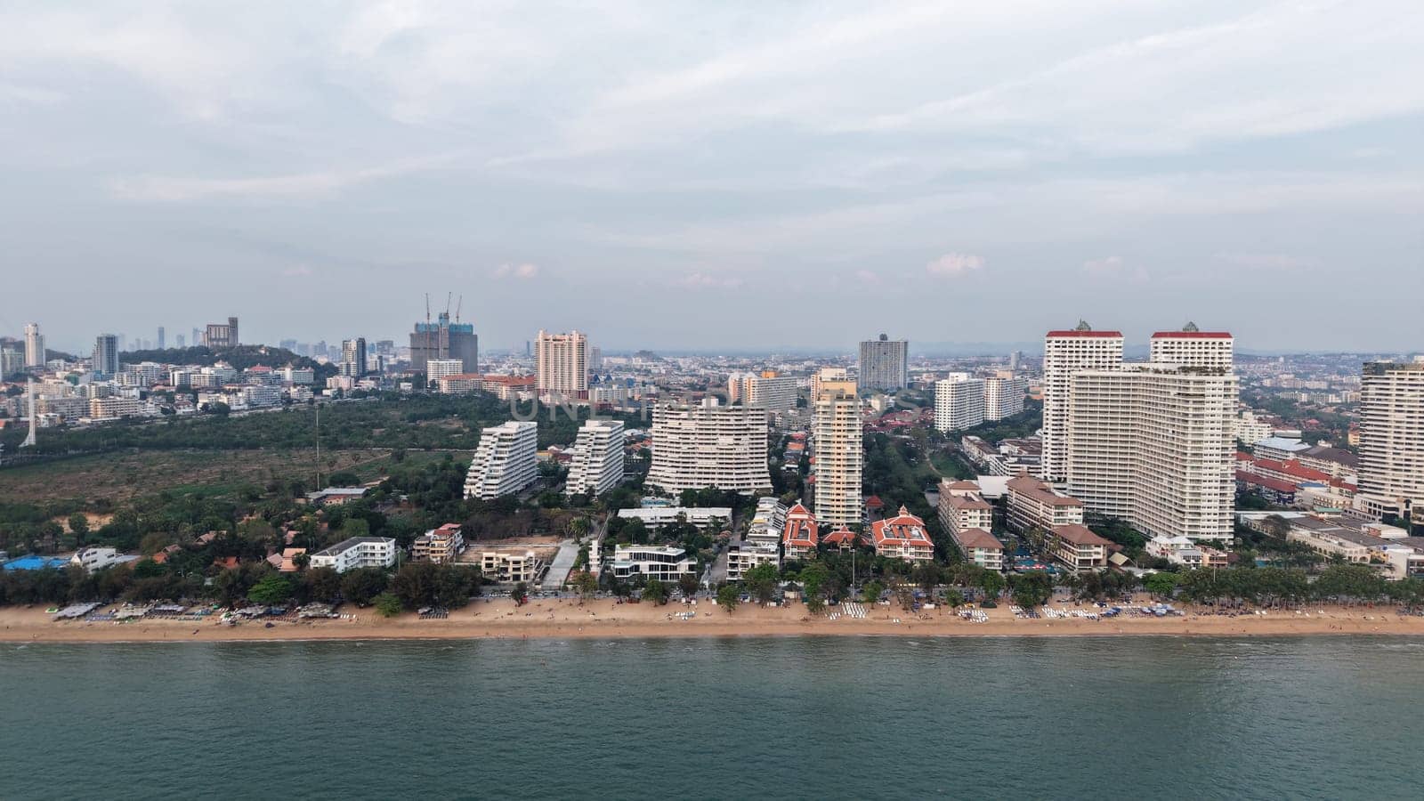 Modern buildings rising along the pattaya coastline create a stunning cityscape against the ocean backdrop as twilight approaches, blending urban development with natural beauty