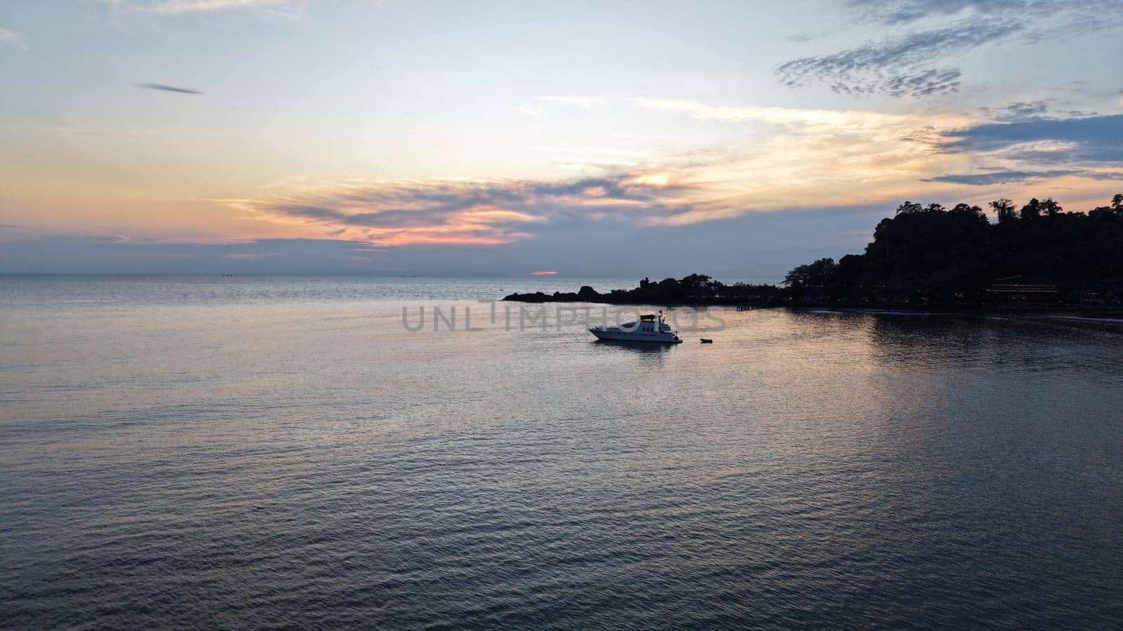 White luxury yacht rocking gently on calm ocean waters near a tropical island, with vibrant sunset hues of orange and pink reflecting on the tranquil sea