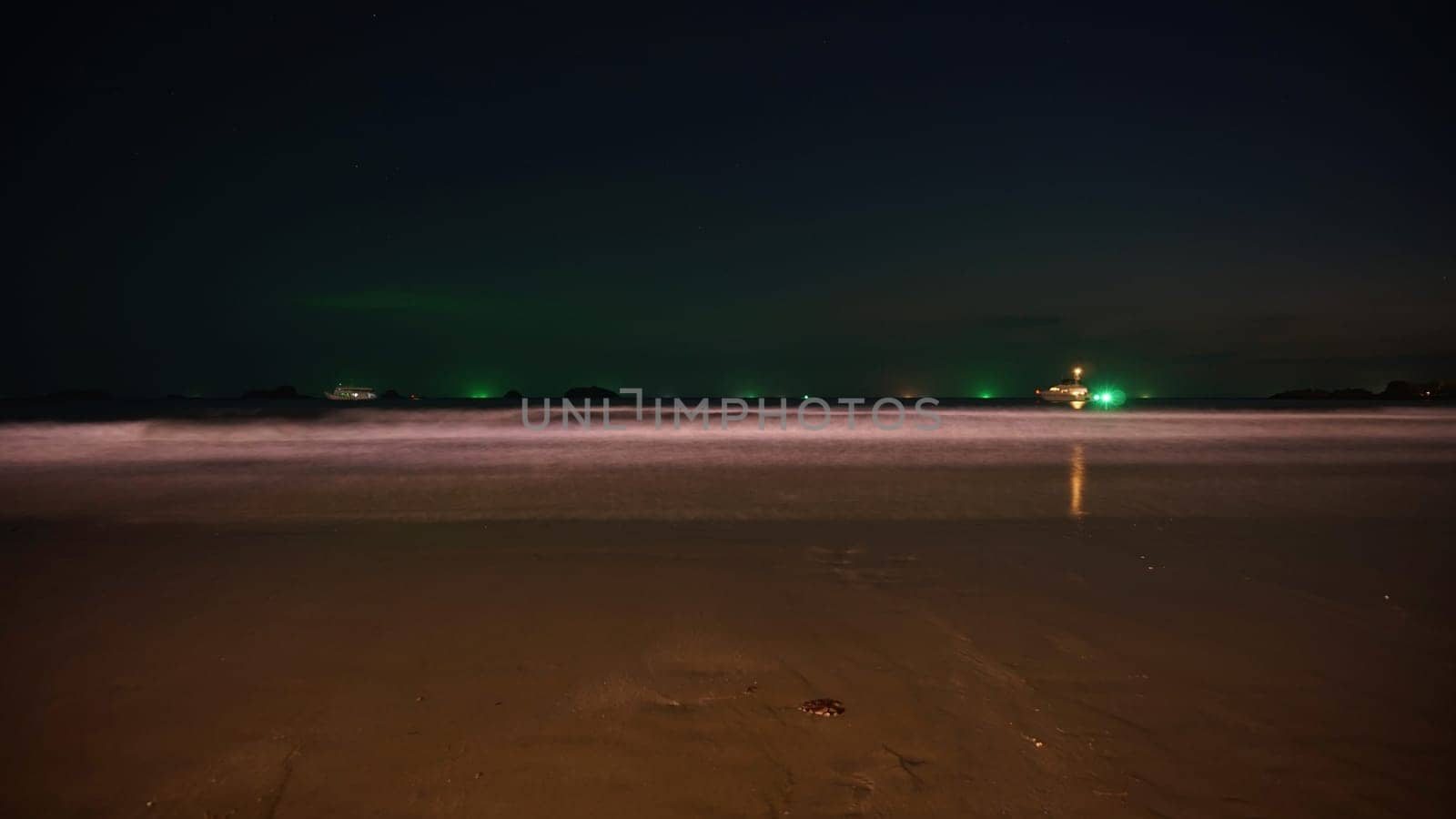 Fishing vessel navigating dark waters, approaching the coast at night, creating a tranquil long exposure seascape with illuminated horizon and smooth waves