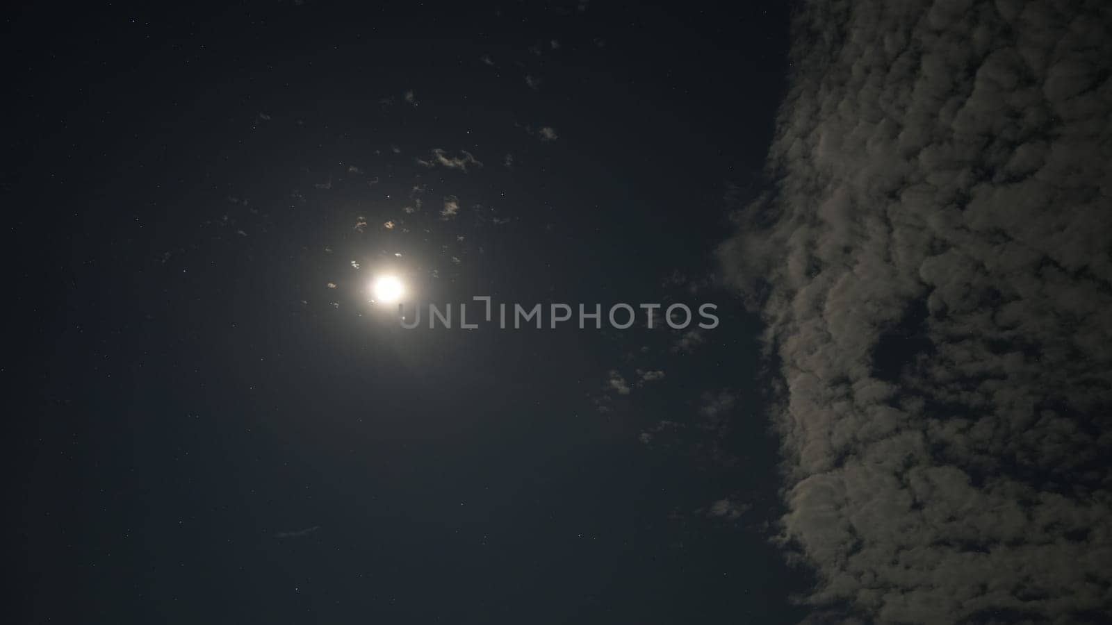 Bright moon illuminating the night sky, shining through scattered clouds and casting a gentle glow, creating a tranquil and serene atmosphere filled with celestial beauty