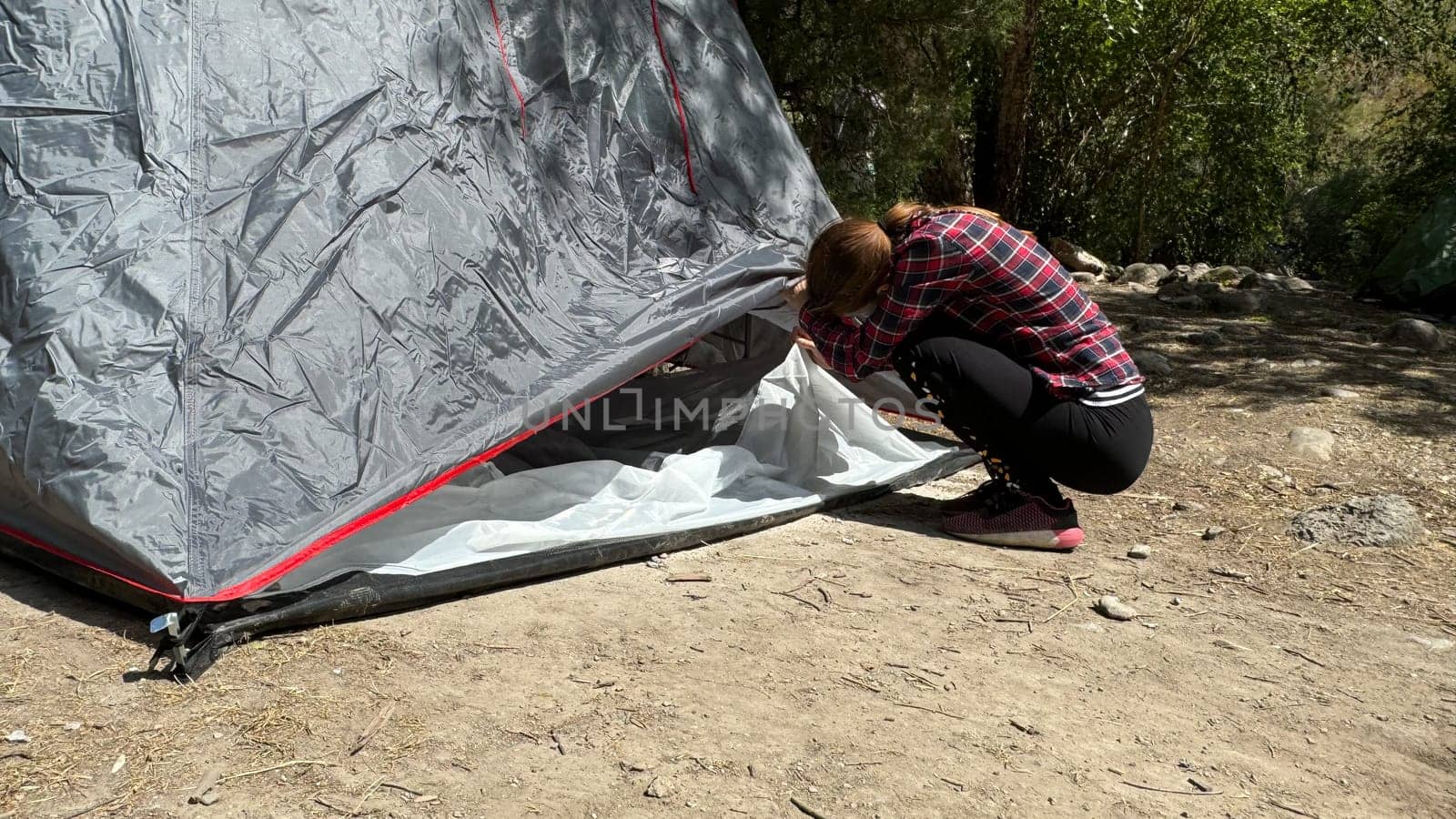 Young woman assembling a tent in a scenic mountain landscape during summer. Outdoor camping activity with clear space for text