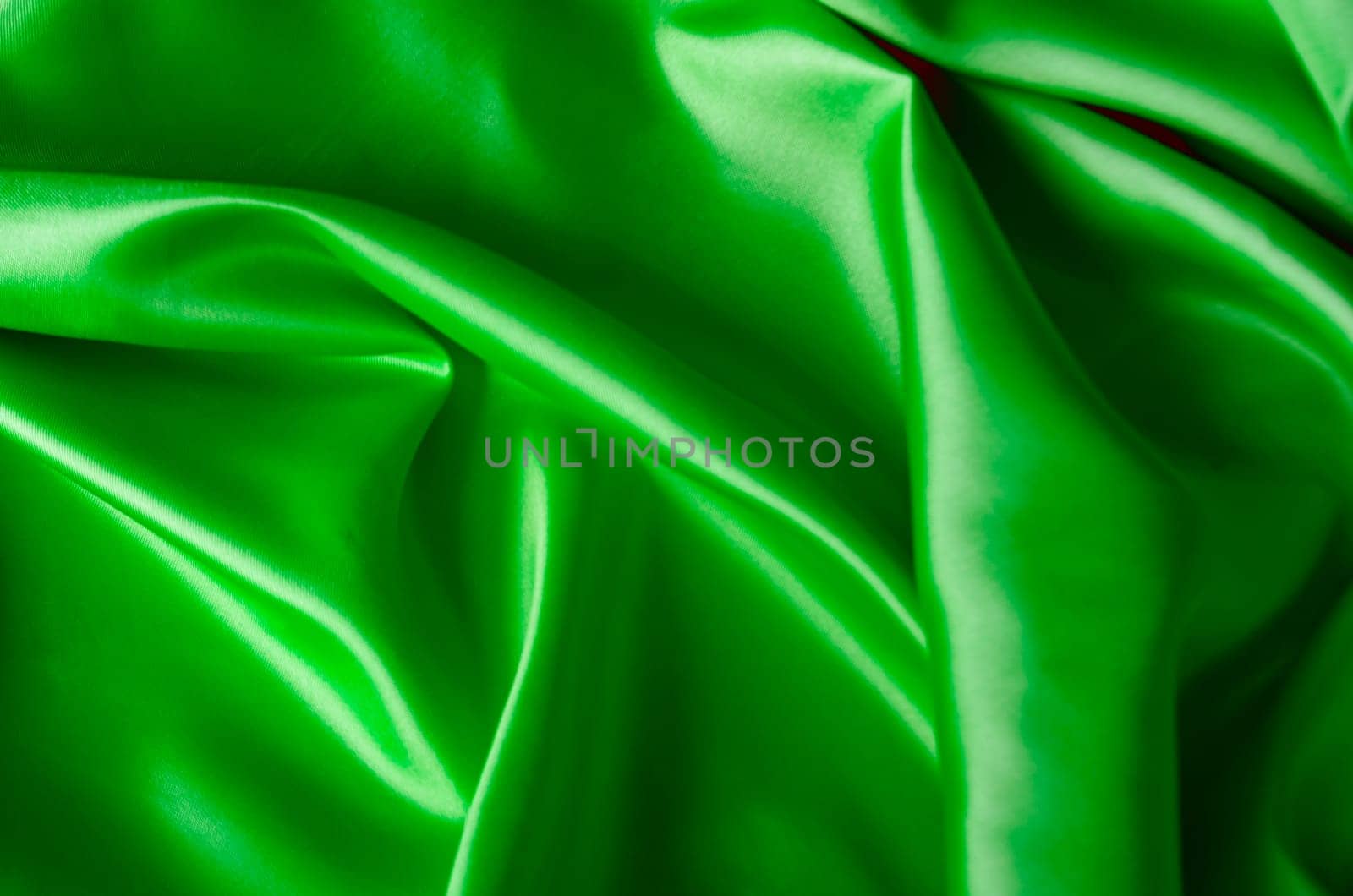 Shining green satin textile with shimmering highlights. Suitable for design and wallpaper background.