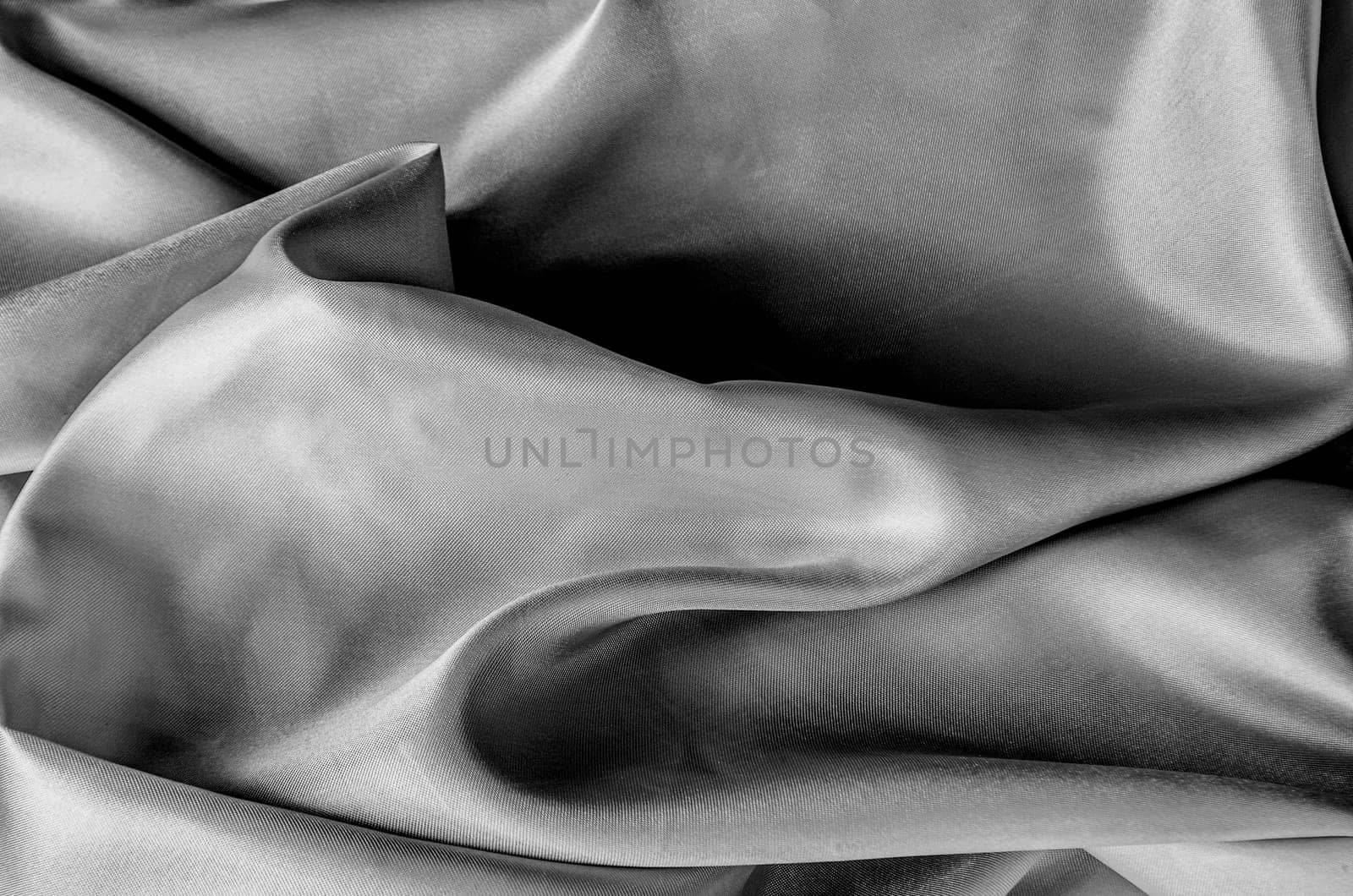 Close up of luxurious black silk fabric with elegant folds and smooth, glossy surface texture