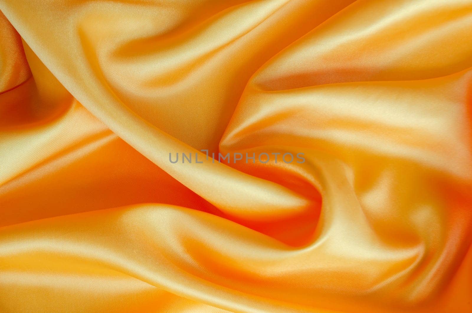 Golden yellow silk draped beautifully with glossy surface and soft highlights. Suitable for design and wallpaper background.