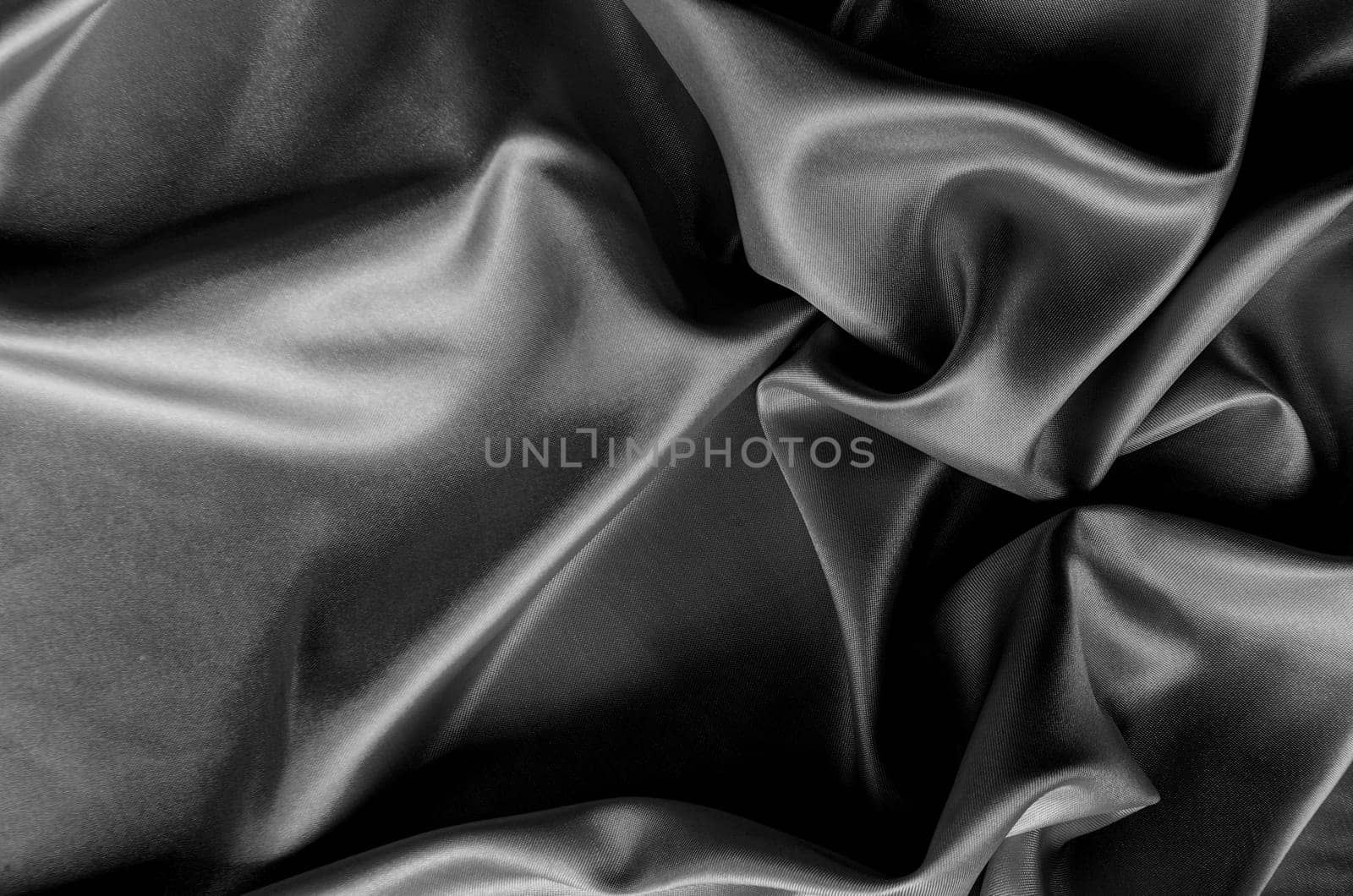 Top view of dark satin fabric with rich texture and smooth, elegant folds. Suitable for design and wallpaper background.