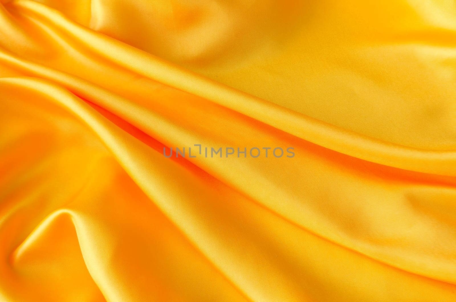Top view of elegant yellow satin textile with shimmering highlights. Suitable for design and wallpaper background.