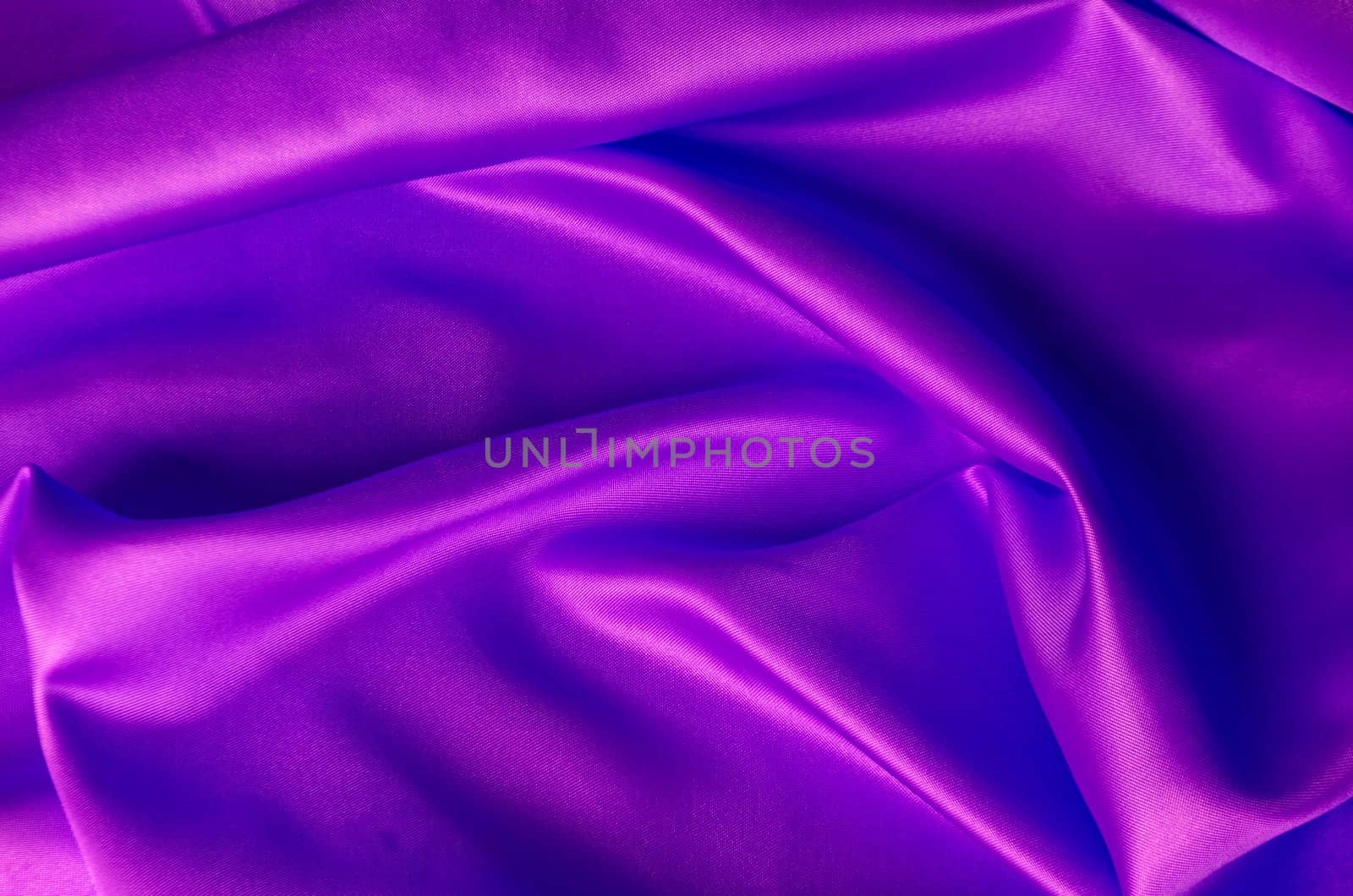 Top view of shiny maroon satin cloth with radiant surface highlights and fine woven texture in natural folds.