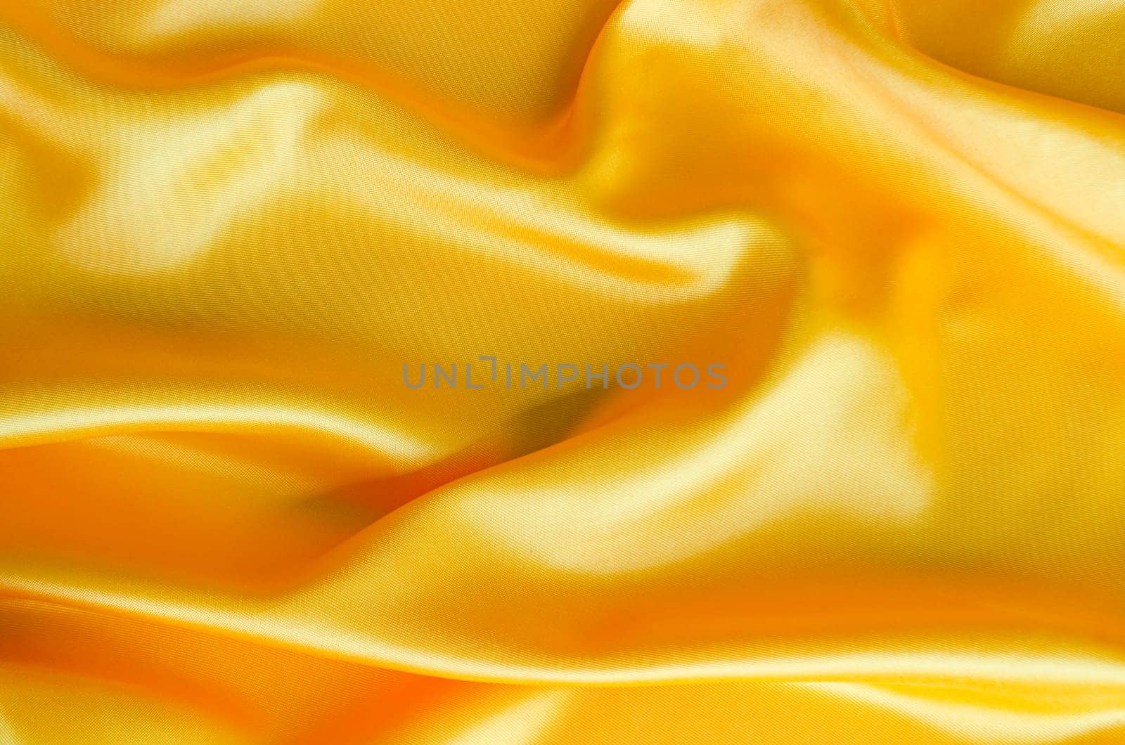 Close up of glossy yellow satin material with smooth surface and folds. Suitable for design and wallpaper background.