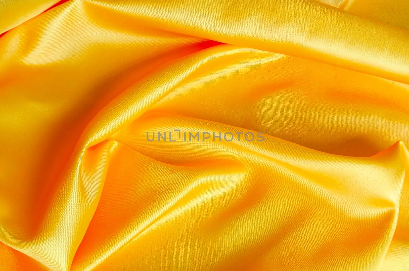 Shiny yellow satin cloth with radiant surface highlights and fine woven texture in natural folds.