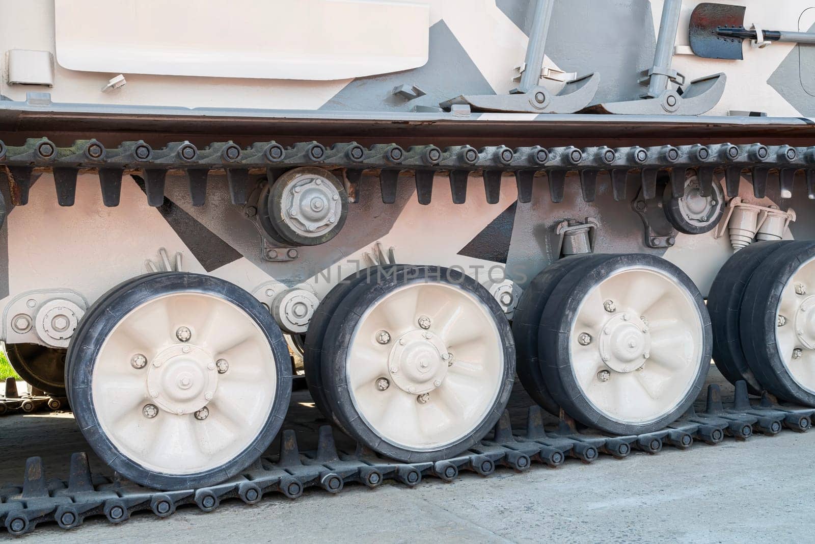 Close-up view of military tank tracks showing wheels and treads. This detailed shot illustrates the engineering and design of armored vehicles in an outdoor exhibition setting.