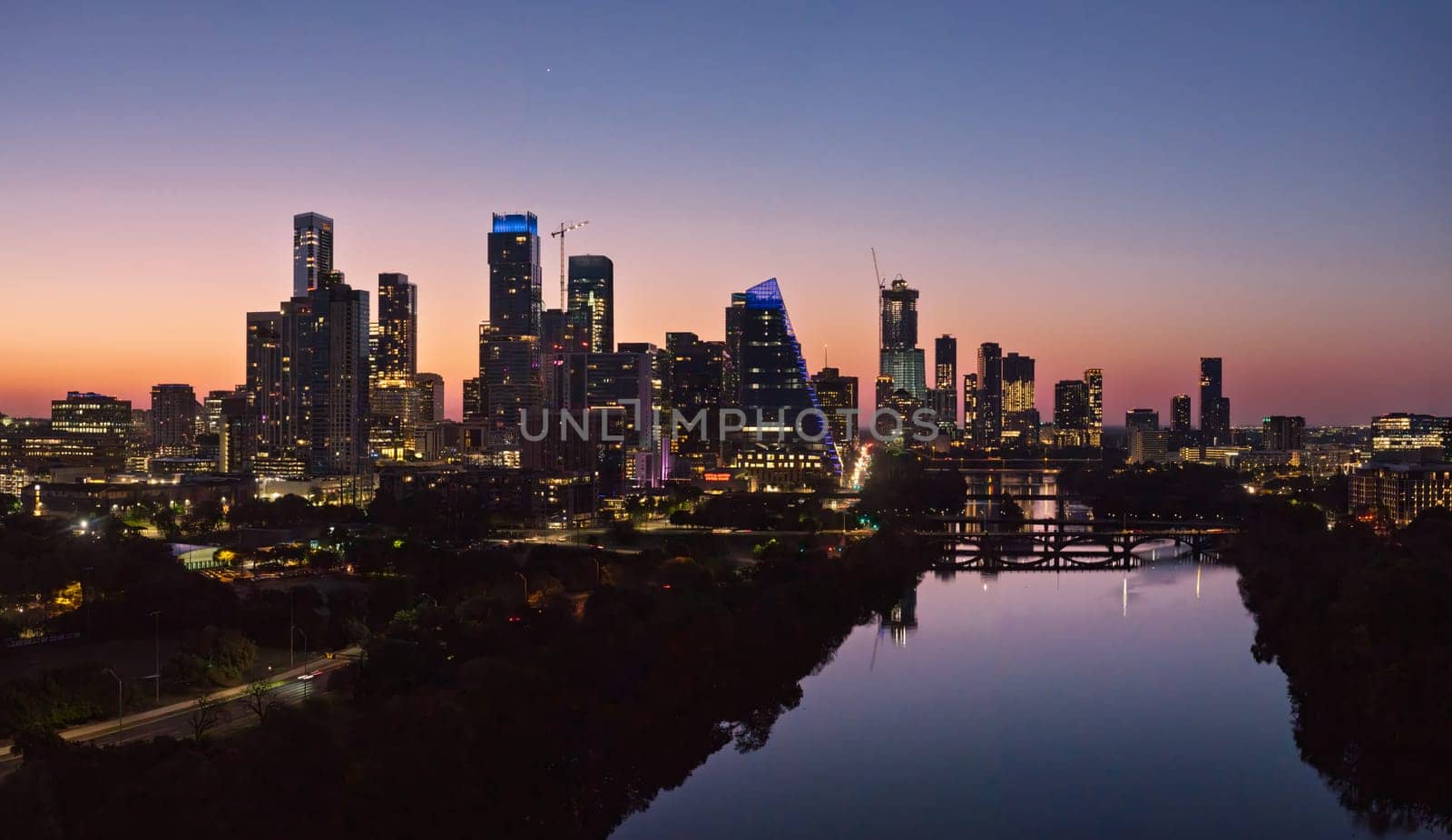 Brilliant orange and red sky behind the illuminated city skyline of Austin Texas before sunrise dawn