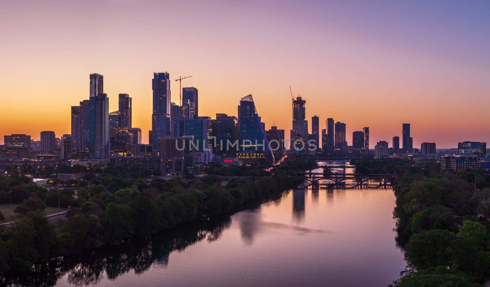 Brilliant orange and red sky behind the illuminated city skyline of Austin Texas before sunrise dawn