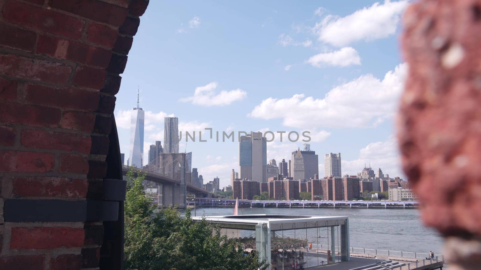 New York City, United States - 30 Aug 2023: Manhattan downtown skyline, waterfront cityscape from Time Out Market. Riverfront Carousel in Dumbo near Brooklyn Bridge. World Trade Center skyscraper.