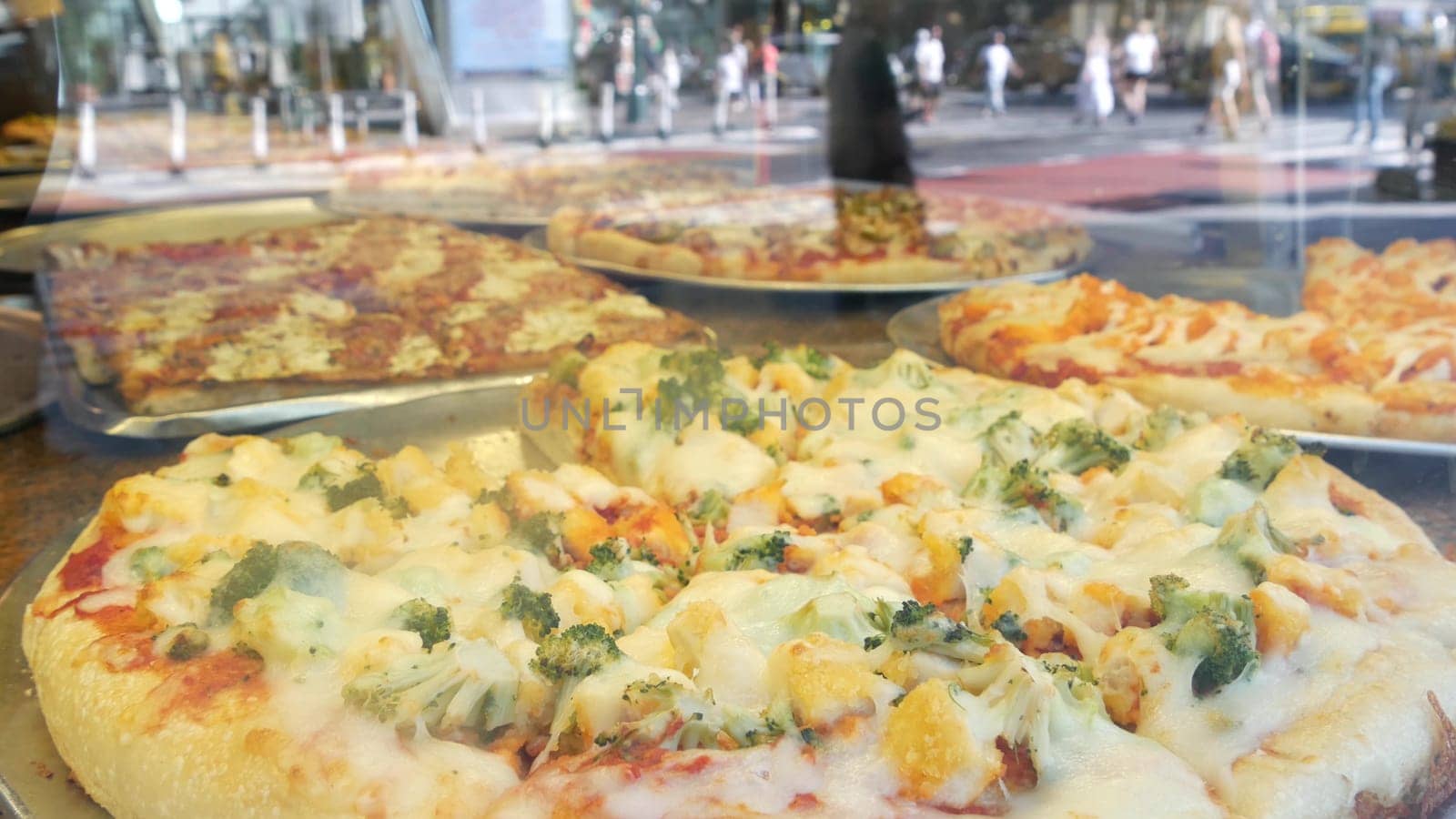 New York City, United States - 4 Sept 2023: Manhattan Midtown 42 street. Fast food big large american pizza, pizzeria restaurant counter. People pedestrian and car traffic reflection, USA. Urban life.